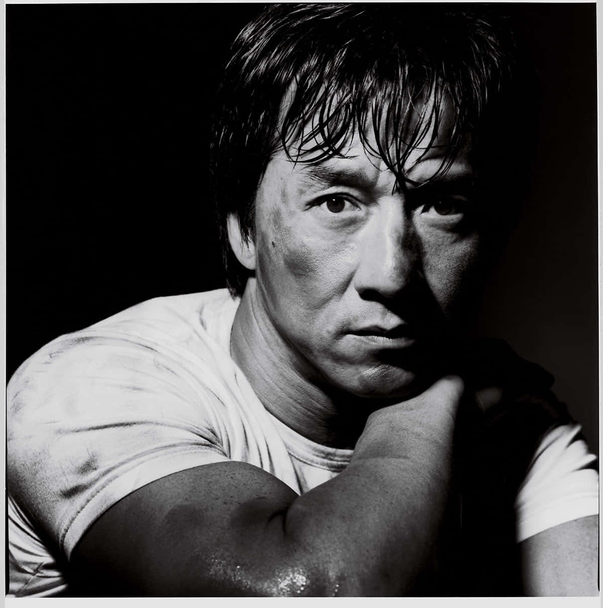 Black And White Celebrity 桌布 壁紙 — 一個戲劇性的黑白肖像，一個濕髮的男人在黑暗背景中將下巴擱在手上。