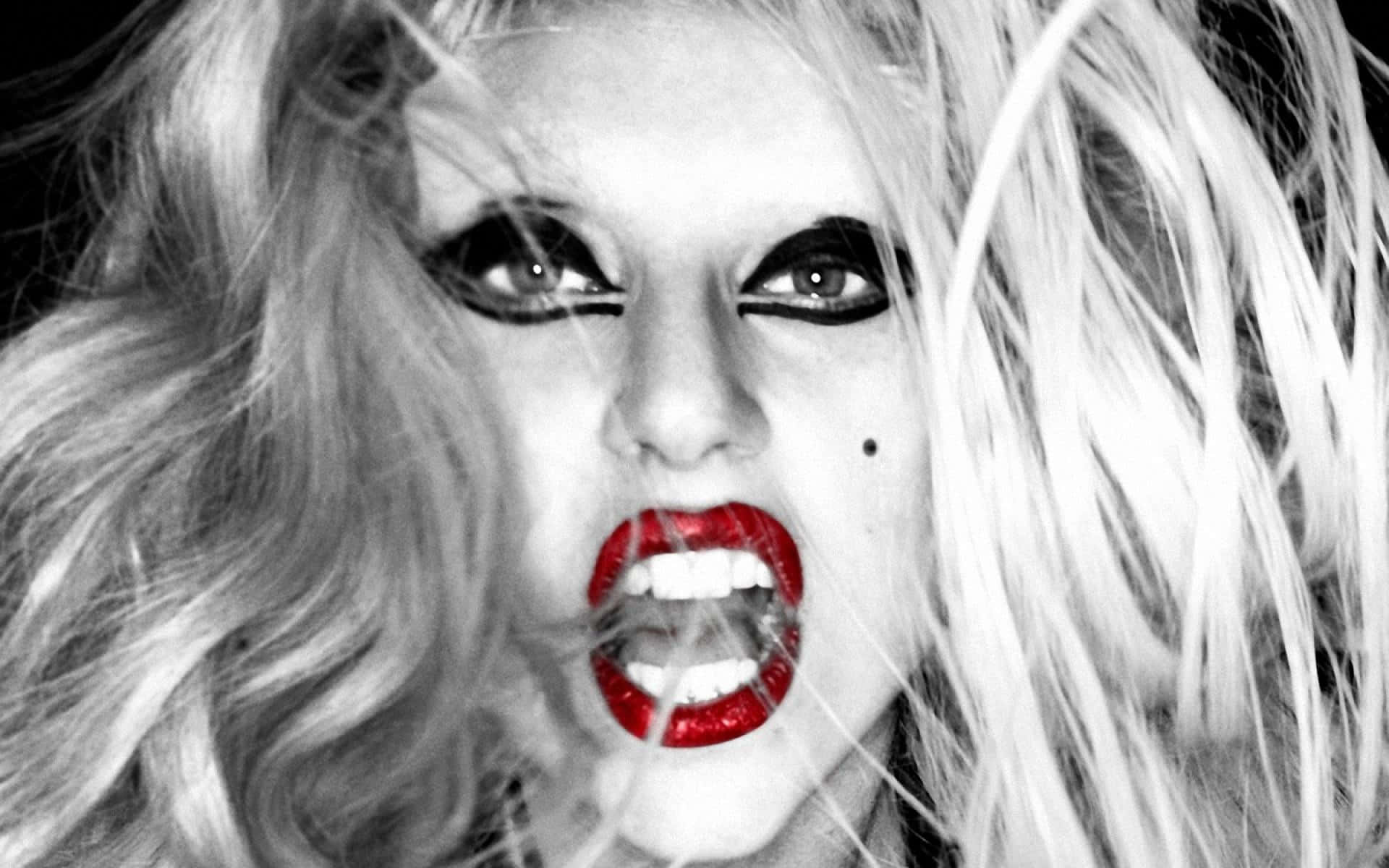 Lady Gaga 桌布 壁紙 — 一個戲劇性的黑白肖像，描繪一位擁有鮮豔紅唇和狂野金髮的女人正在激烈尖叫。