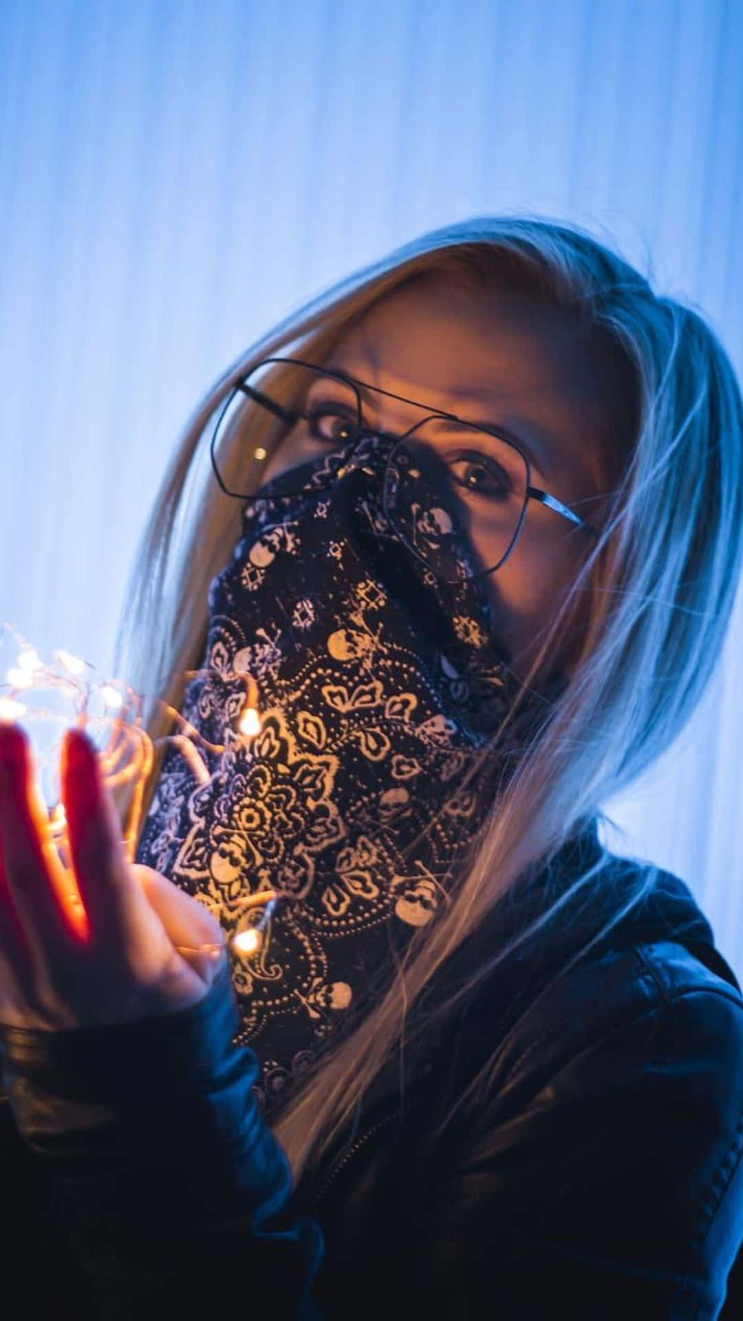 girls 桌布 壁紙 — 一個戴眼鏡和圖案頭巾的人，在冷藍色背景下拿著發光的仙女燈。