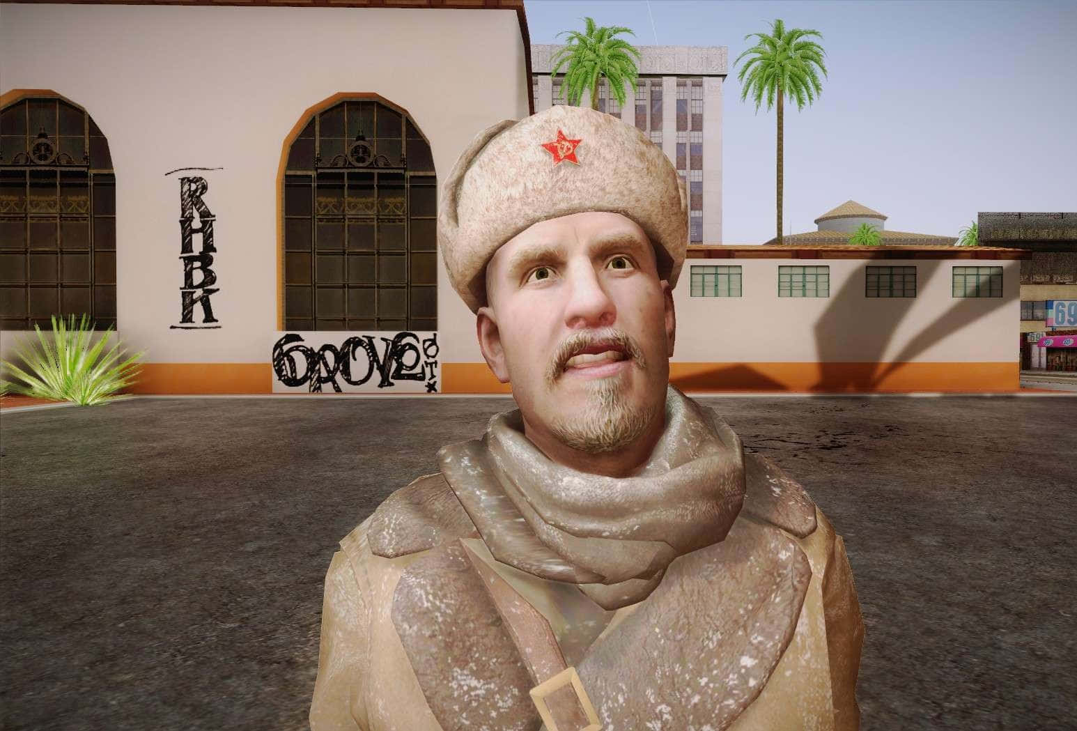 Viktor Reznov 桌布 壁紙 — 一個戴着帶有紅星的蘇聯風格毛帽的男人，站在一個陽光普照、有棕櫚樹和塗鴉建築物的城市庭院中。