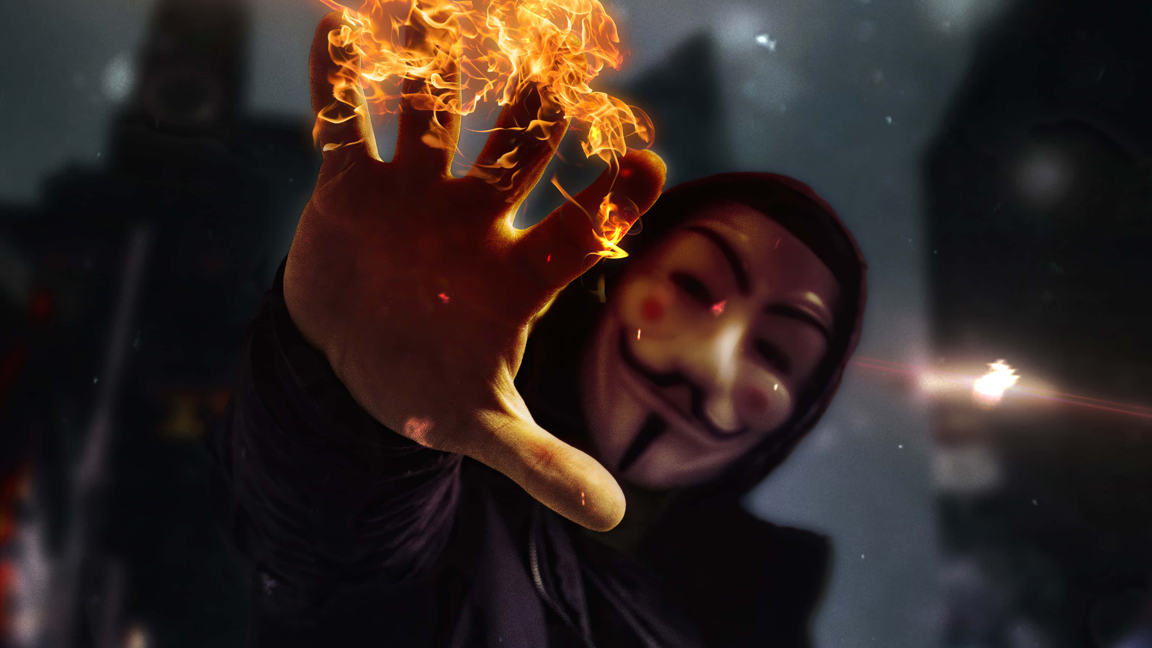 Anonymous 桌布 壁紙 — 一個戴着蓋伊·福克斯面具的人，在黑暗的城市背景下，向觀看者伸出一隻燃燒的手。