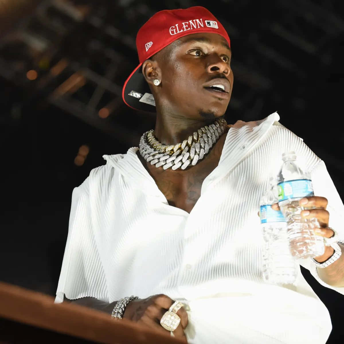 Dababy 桌布 壁紙 — 一個戴紅色帽、穿白色褶襯衫嘅男人，拎住一個水樽，同時戴住一條粗鑽石鏈同戒指。