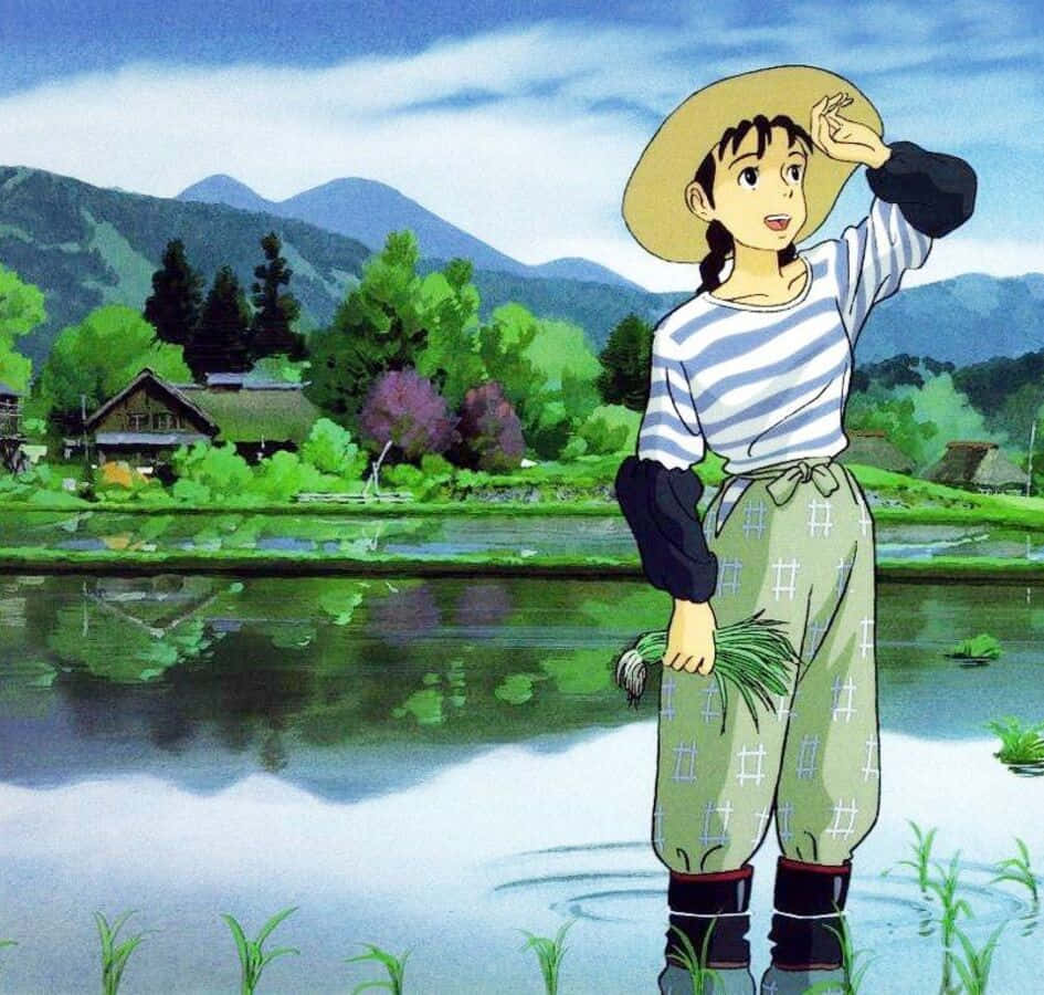 Only Yesterday 桌布 壁紙 — 一個戴草帽嘅年輕女仔企喺稻田入面，手拎住綠色嘅稻稈，背後有山同村莊，喺晴朗嘅藍天之下。
