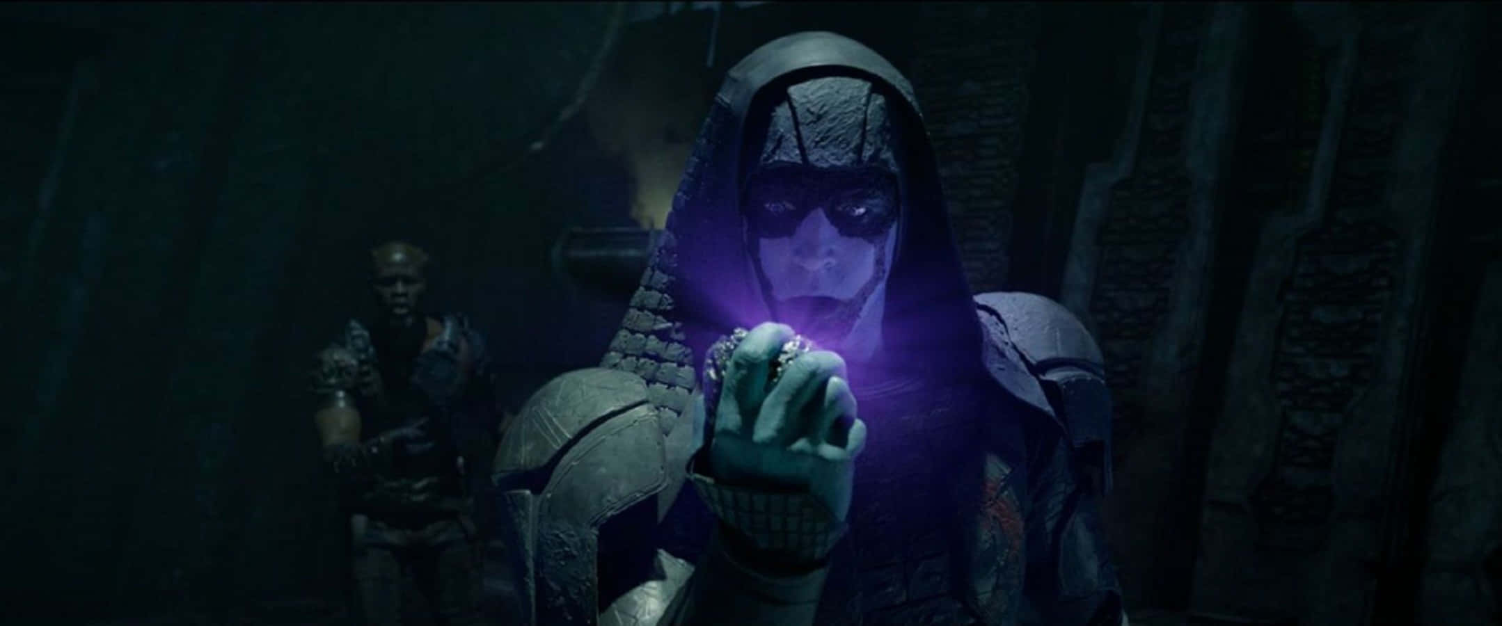 Kree 桌布 壁紙 — 一個戴著兜帽、身穿暗色鎧甲的身影在陰暗的石室中手持一個發光的紫色球體。
