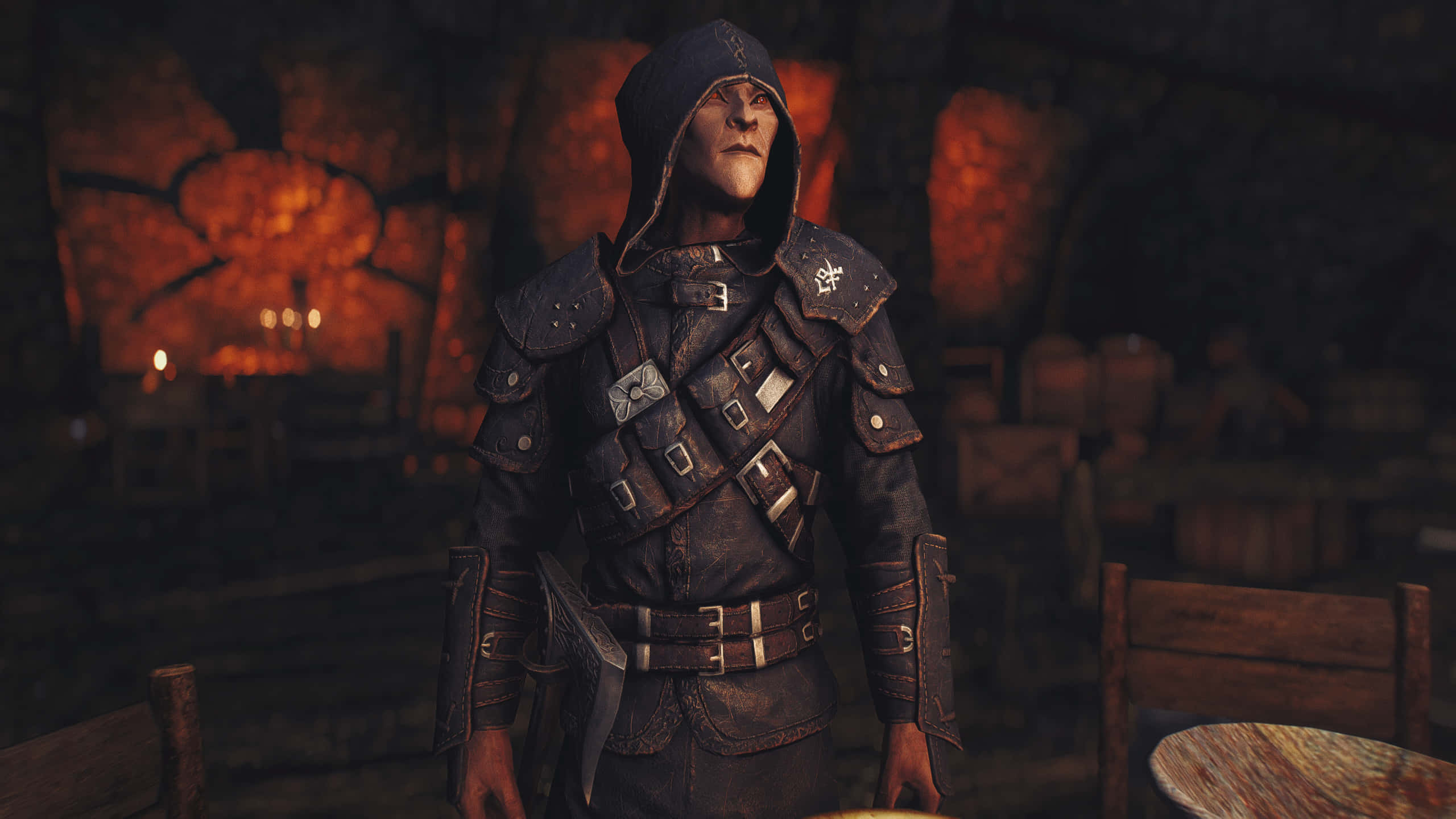 Thieves Guild 桌布 壁紙 — 一個戴著兜帽的裝甲戰士站在一個昏暗的燭光酒館裡，有石牆和木製家具。