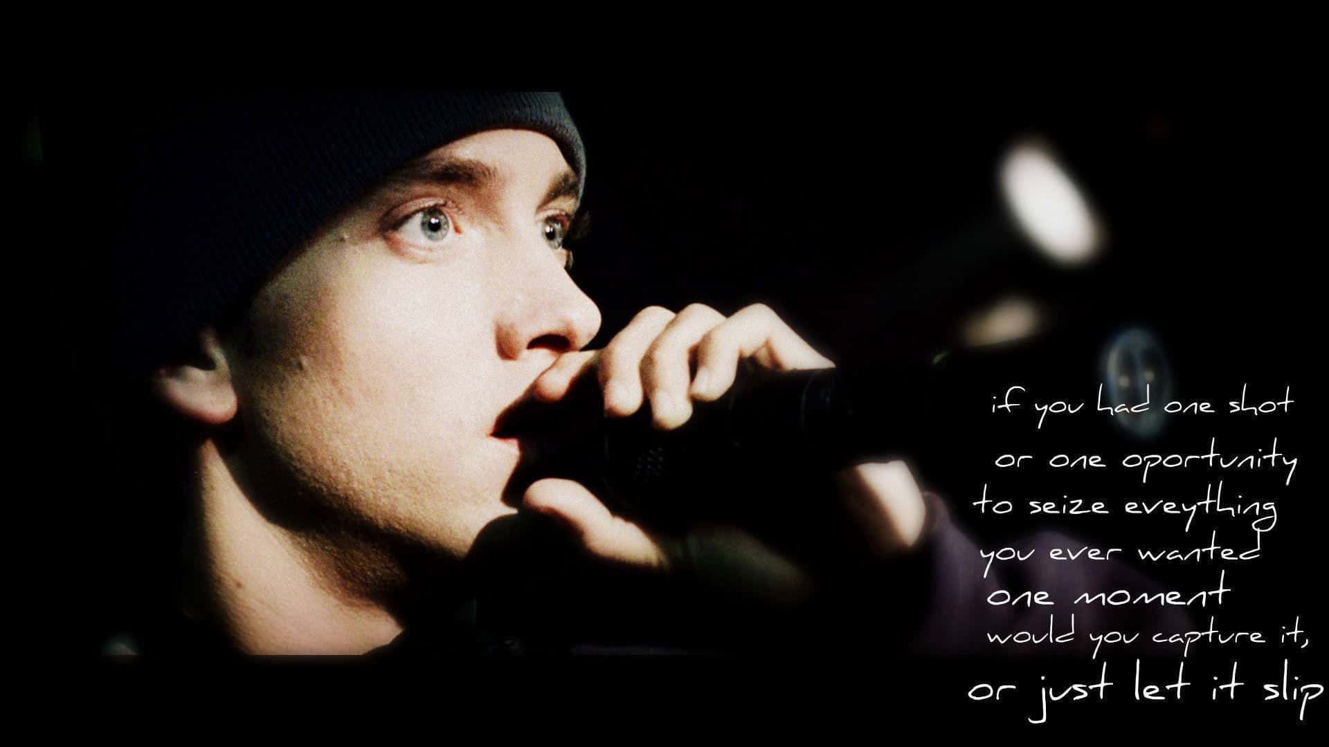 Eminem 桌布 壁紙 — 一個戴著冷帽的男人特寫，在黑暗背景中手持麥克風，帶有發光文字疊加。