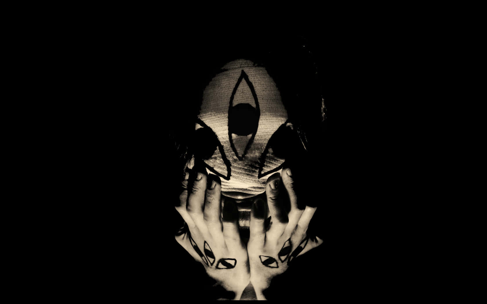 Occult 桌布 壁紙 — 一個戴著幾何面具並有匹配手部紋身的人，在黑暗中捧著自己的臉。
