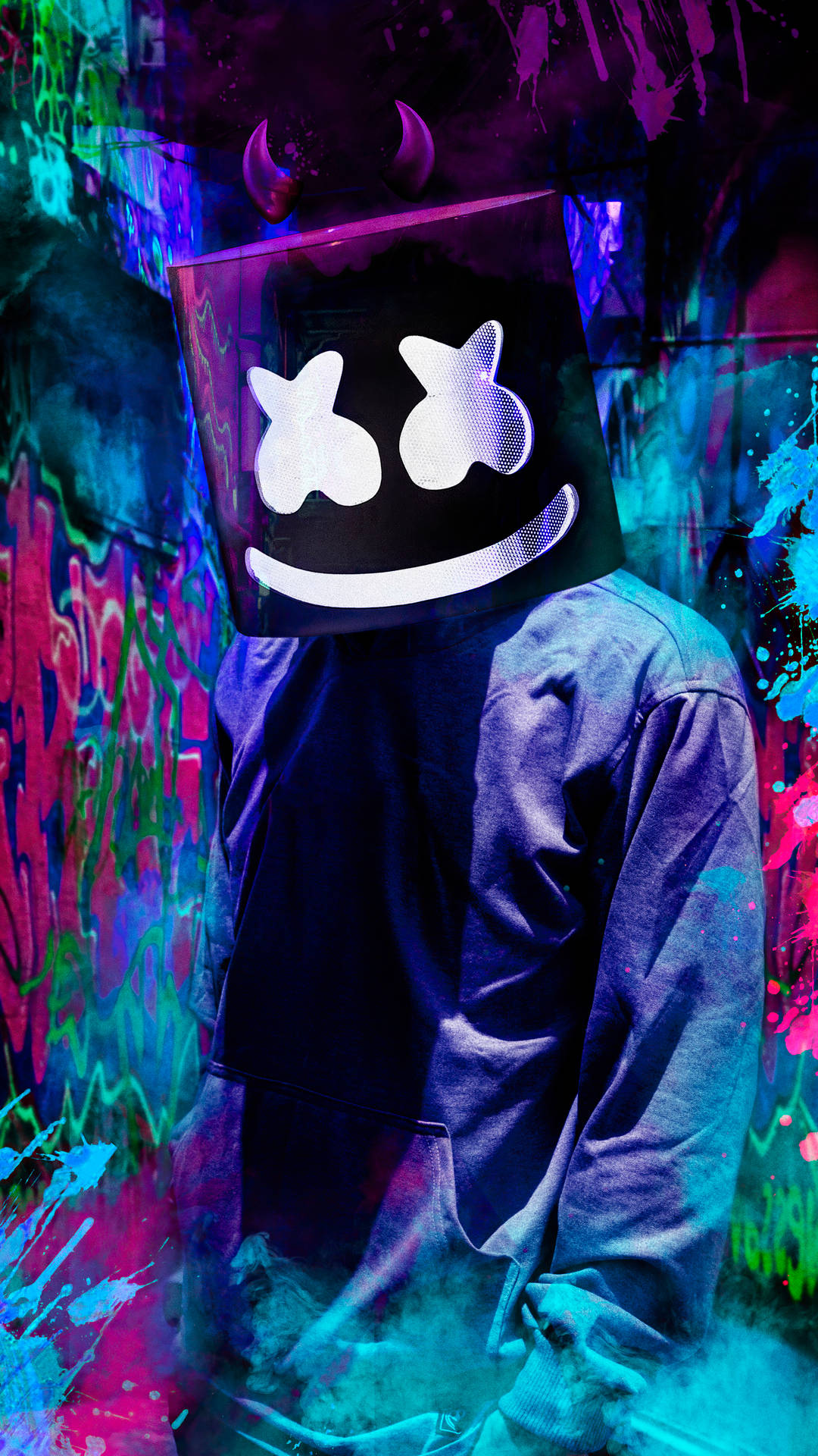 marshmello iPhone 桌布 壁紙 — 一個戴著發光Marshmello面具的人物，在霓虹燈下站在充滿活力的塗鴉飛濺之中。