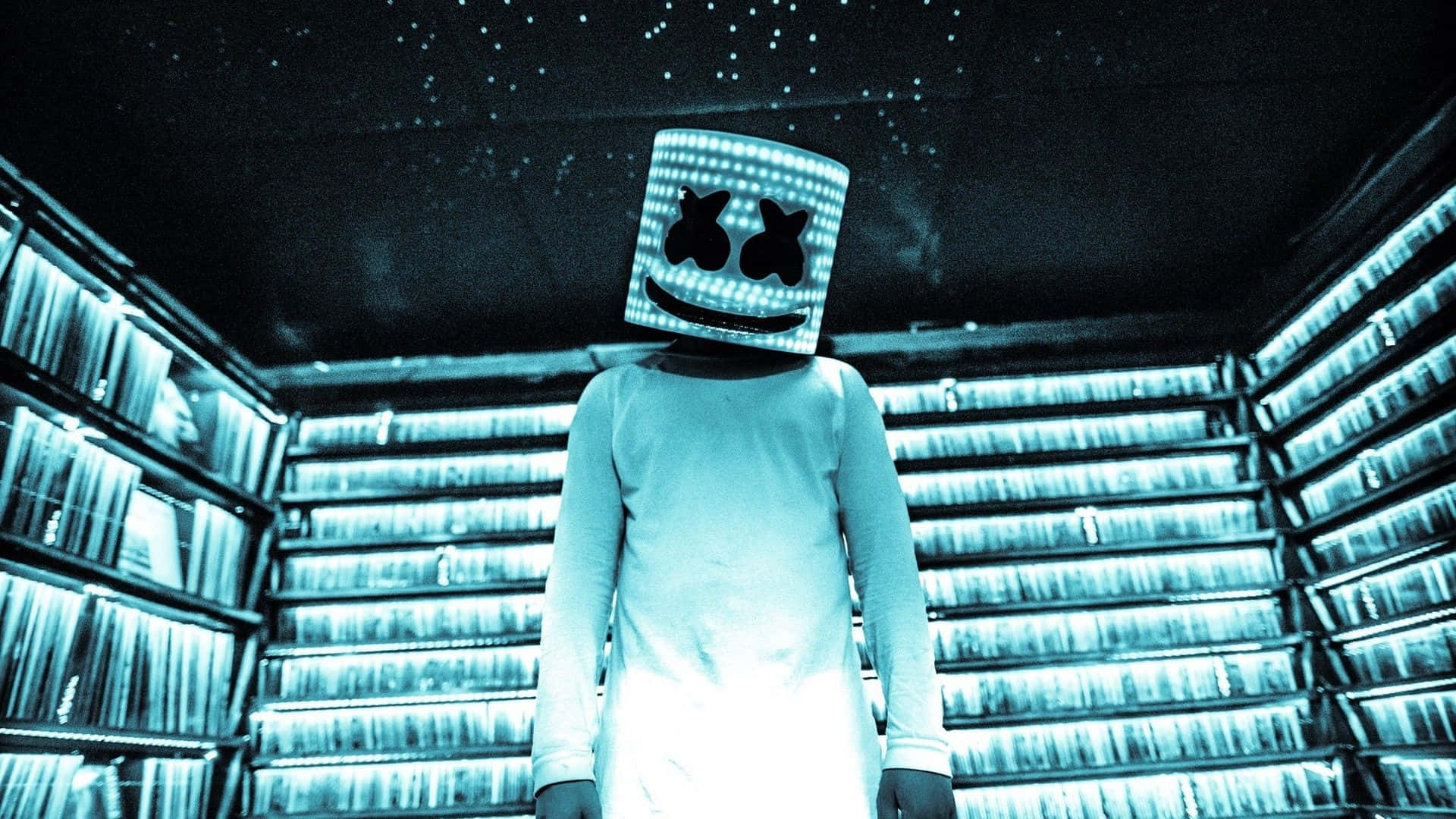 Marshmello 桌布 壁紙 — 一個戴著發光笑臉面具的人物站在一個滿是星星的房間裡，周圍是發光的書架。