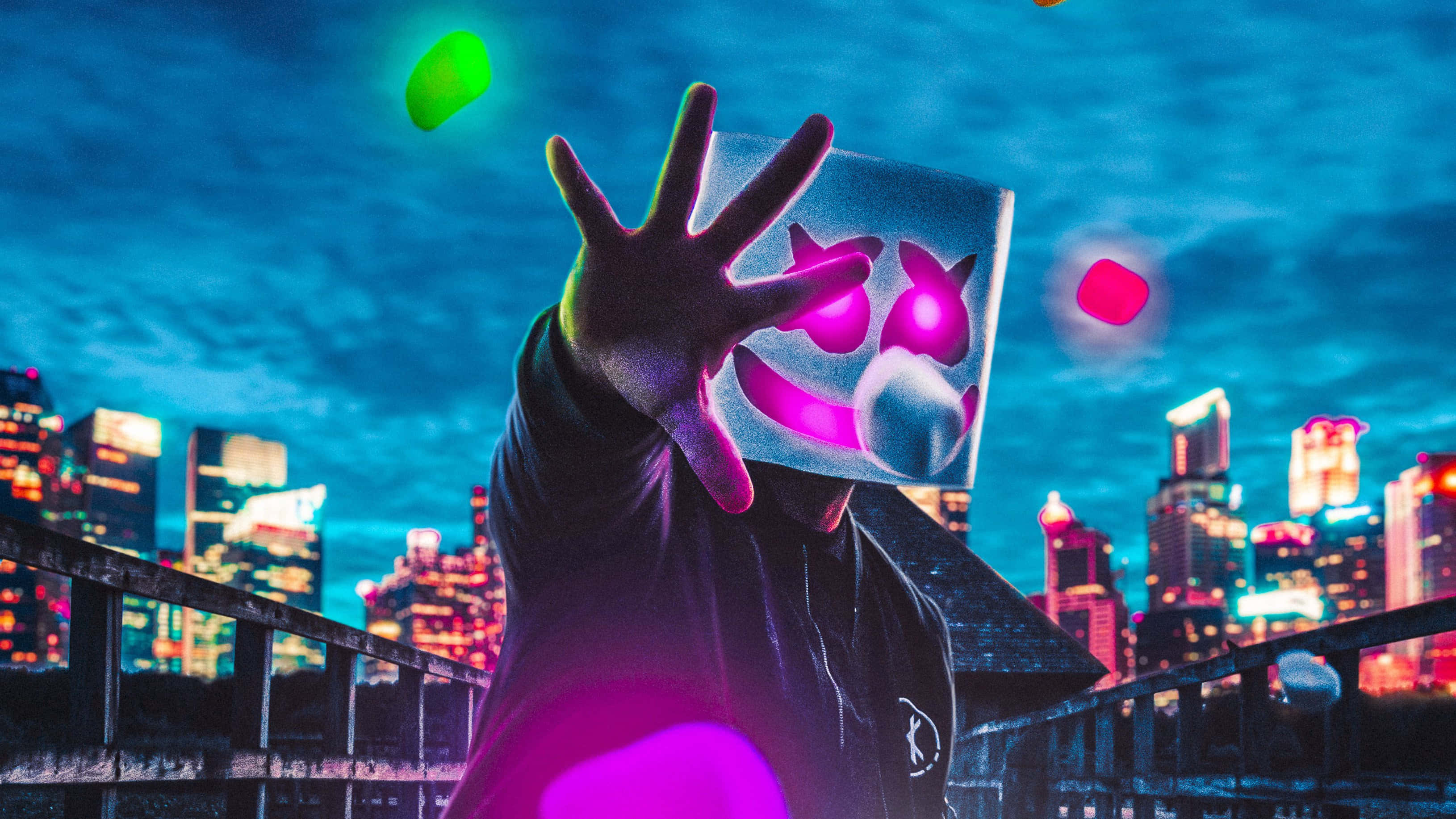 Marshmello 桌布 壁紙 — 一個戴著發光粉紅色面具和黑色連帽衫的人夜晚站在屋頂上，向著充滿活力的霓虹燈城市天際線伸出一隻手。