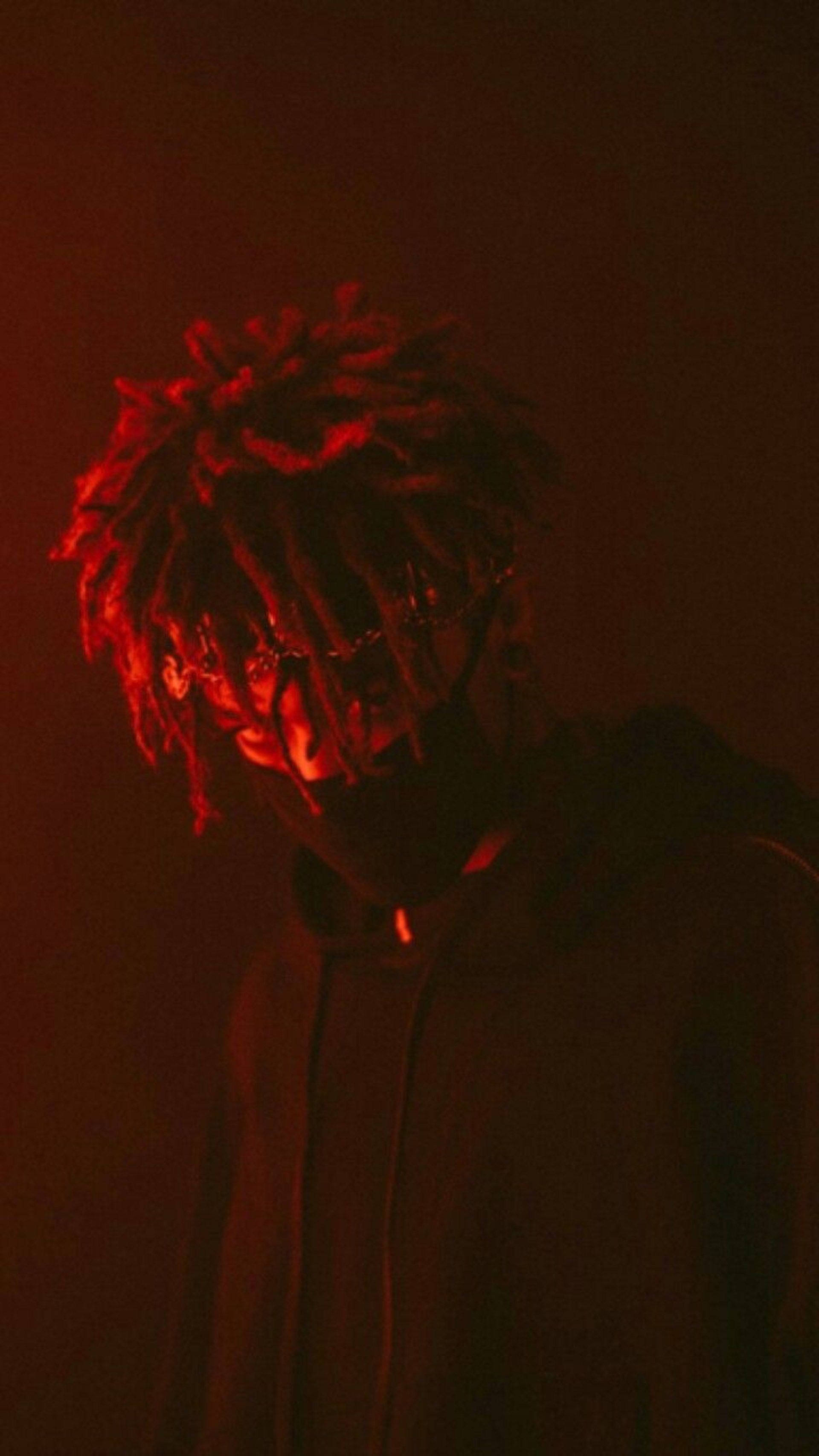 Scarlxrd LIES YXU TELL 壁紙 — 一個戴著眼鏡、梳著辮子的人，在黑暗背景下沐浴在強烈的紅光中。