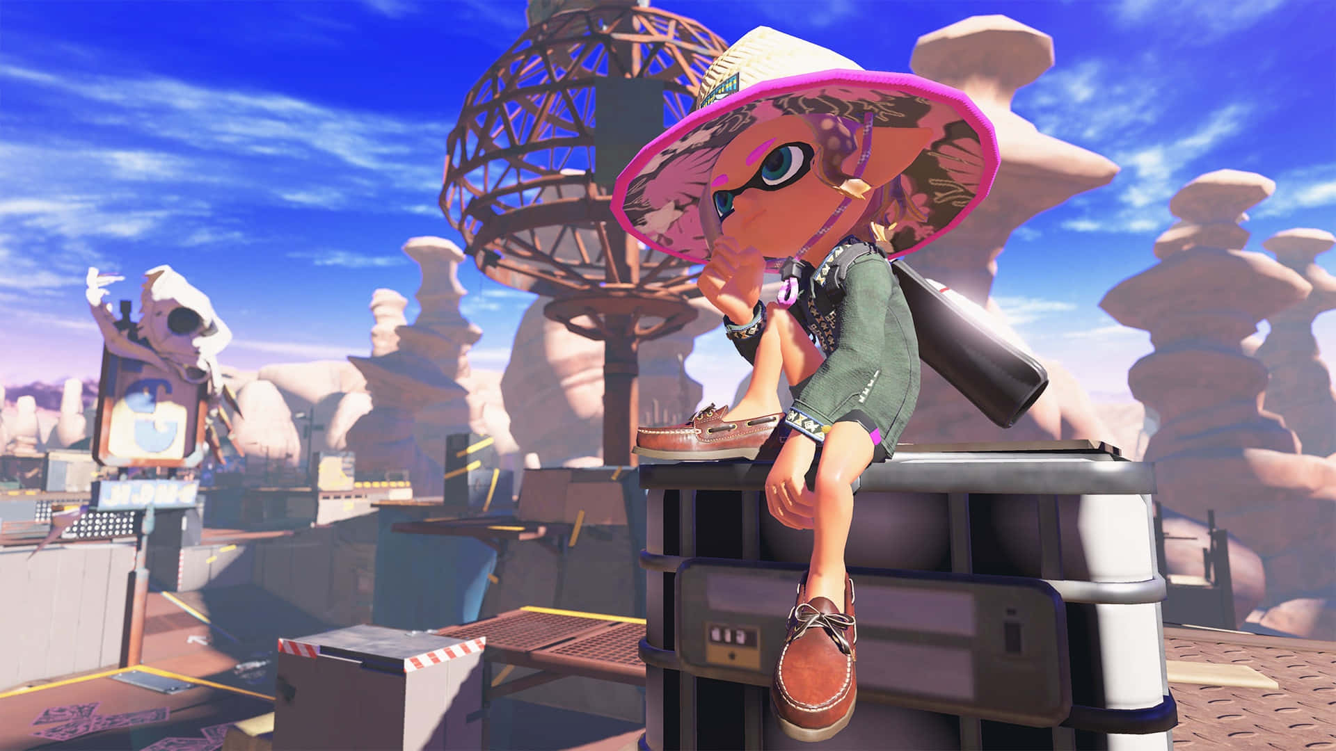 splatoon 桌布 壁紙 — 一個戴著粉紅色帽子的風格化魷魚角色坐在一個木箱上，身處一個有岩石形成和藍天的沙漠風格遊戲世界。