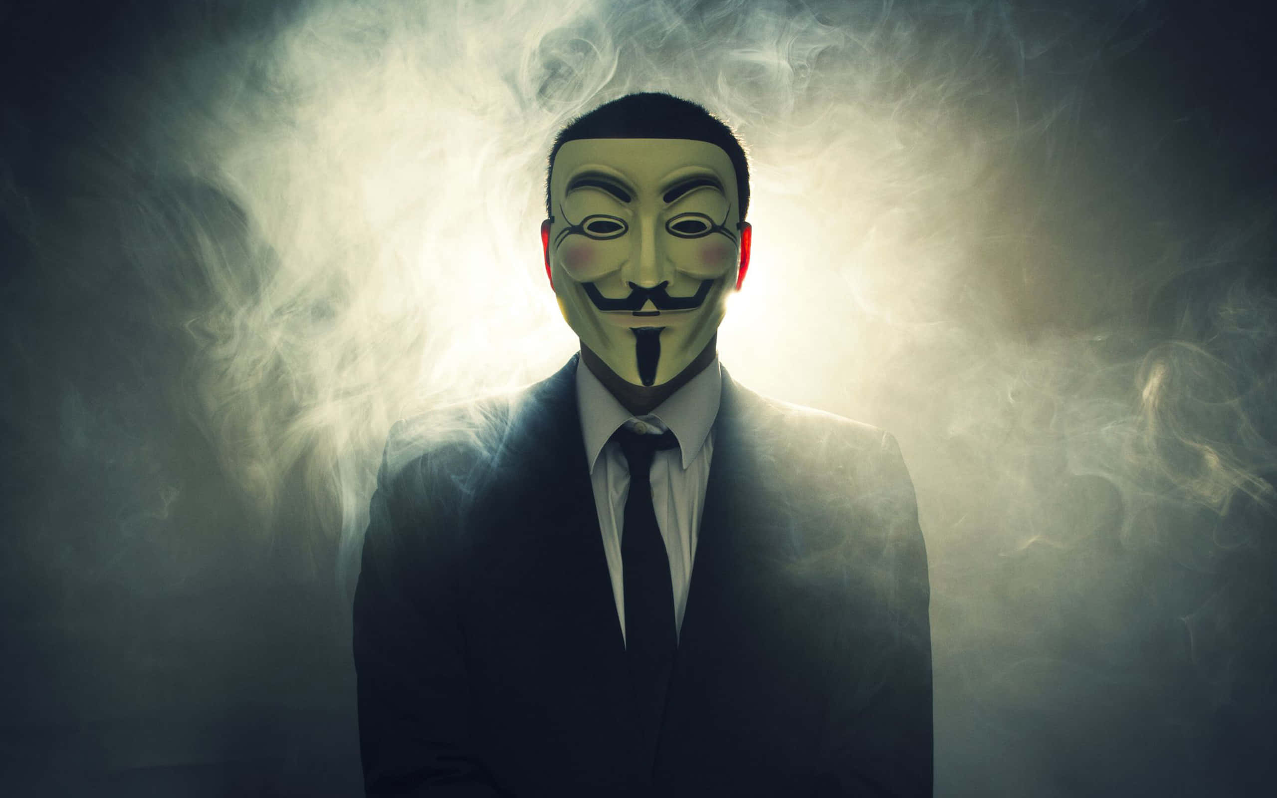 Anonymous 桌布 壁紙 — 一個戴著蓋伊·福克斯面具和西裝的人，在黑暗環境中背光照射，背景是旋轉的煙霧。