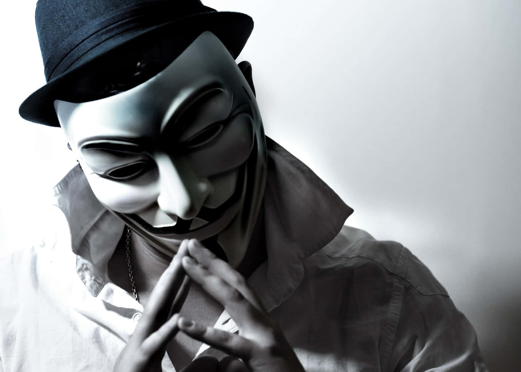 Anonymous 桌布 壁紙 — 一個戴著蓋伊·福克斯面具和軟呢帽的人，在純色背景前做手勢。