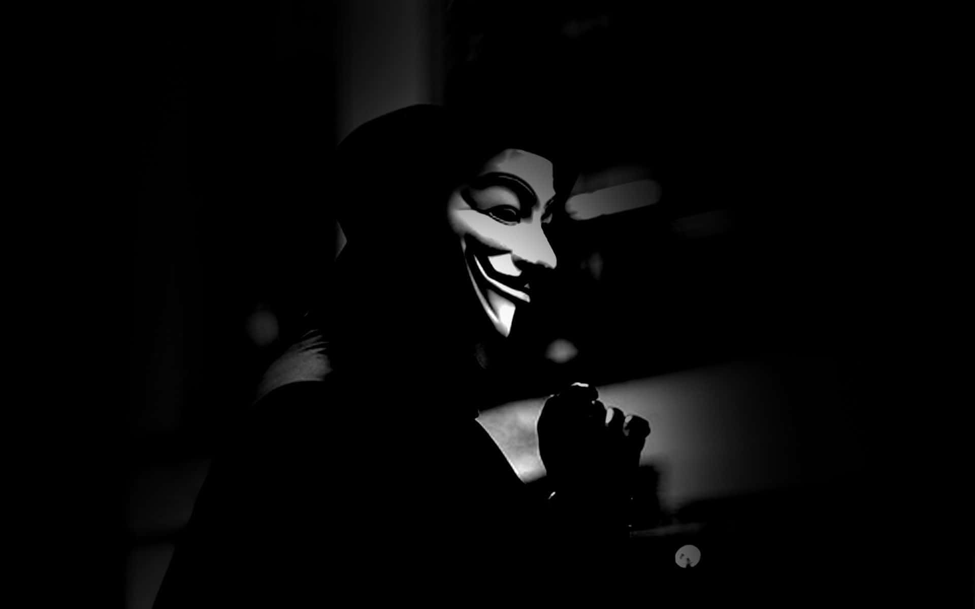 Anonymous 桌布 壁紙 — 一個戴著蓋伊·福克斯面具的人，在昏暗的光線下以剪影形式出現在黑暗背景前。