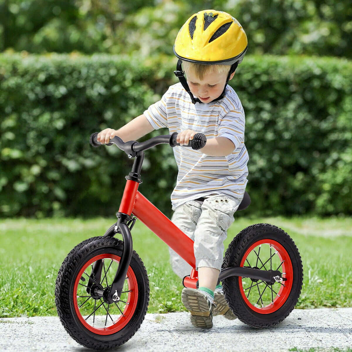 Bicycle 桌布 壁紙 — 一個戴著黃色頭盔的小孩在鋪砌的小路上踩著紅色平衡車穿過鬱鬱蔥蔥的綠色公園。