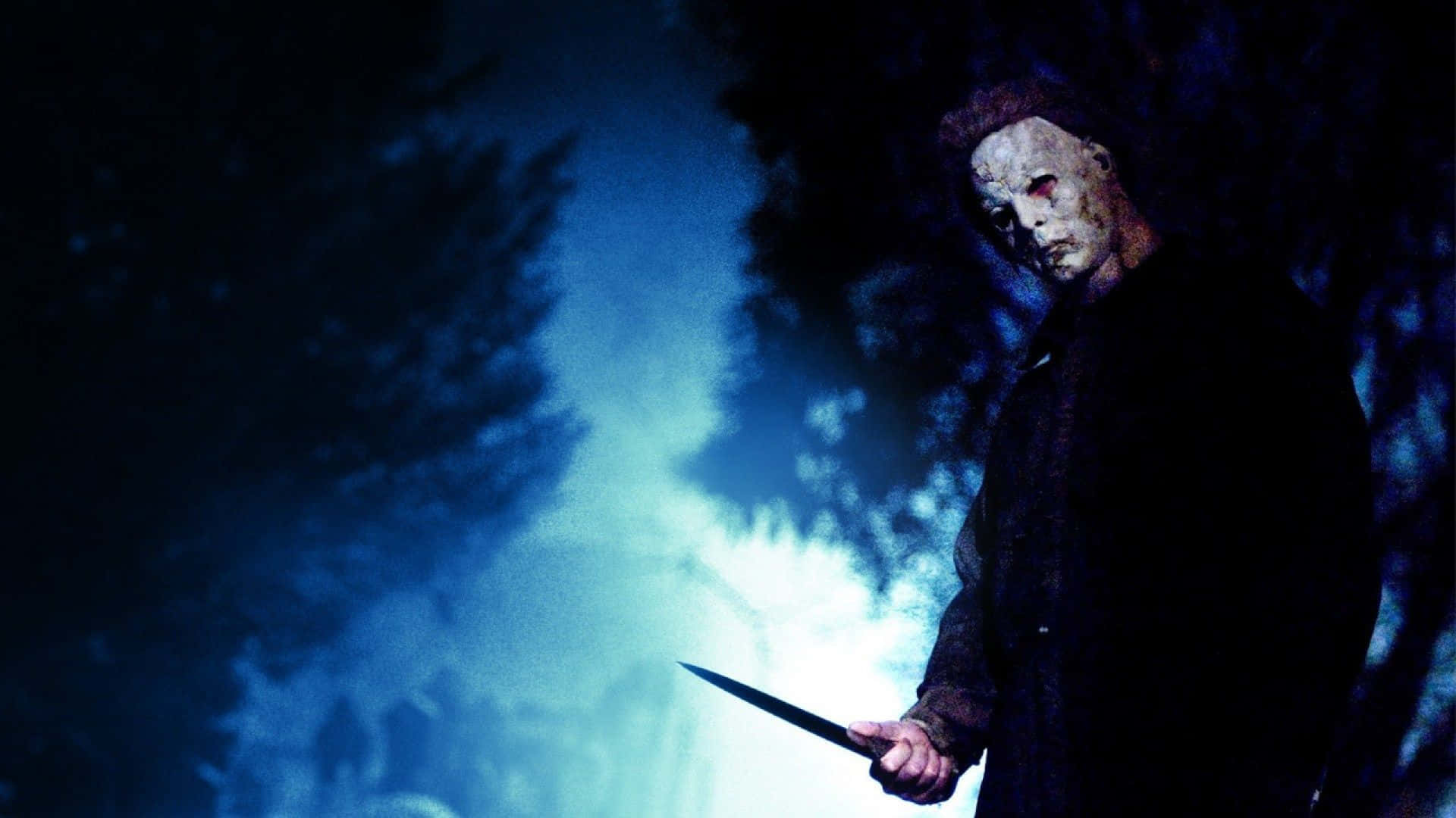 Mike Myers 桌布 壁紙 — 一個戴面具的殺手在黑暗的森林中，在詭異的藍色月光下拿著一把刀。