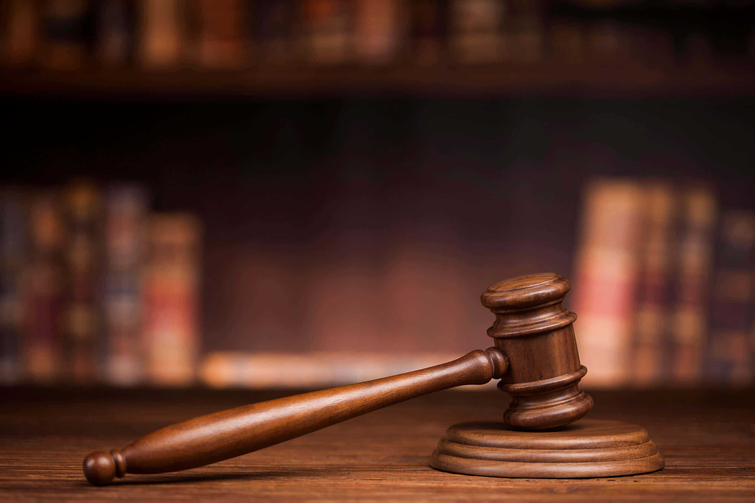 Law 桌布 壁紙 — 一個拋光木槌放在其支架上，置於書桌上，背景是模糊的書架。