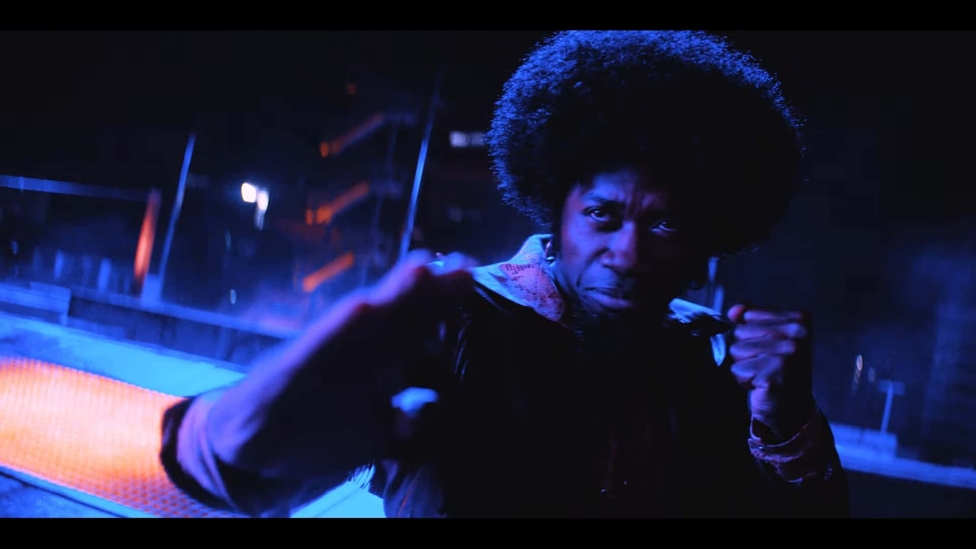 Cowboy Bebop Abdul Hakim 桌布 壁紙 — 一個擁有大型爆炸頭的人站在霓虹燈照亮的城市夜景中，舉起拳頭擺出對抗姿勢。