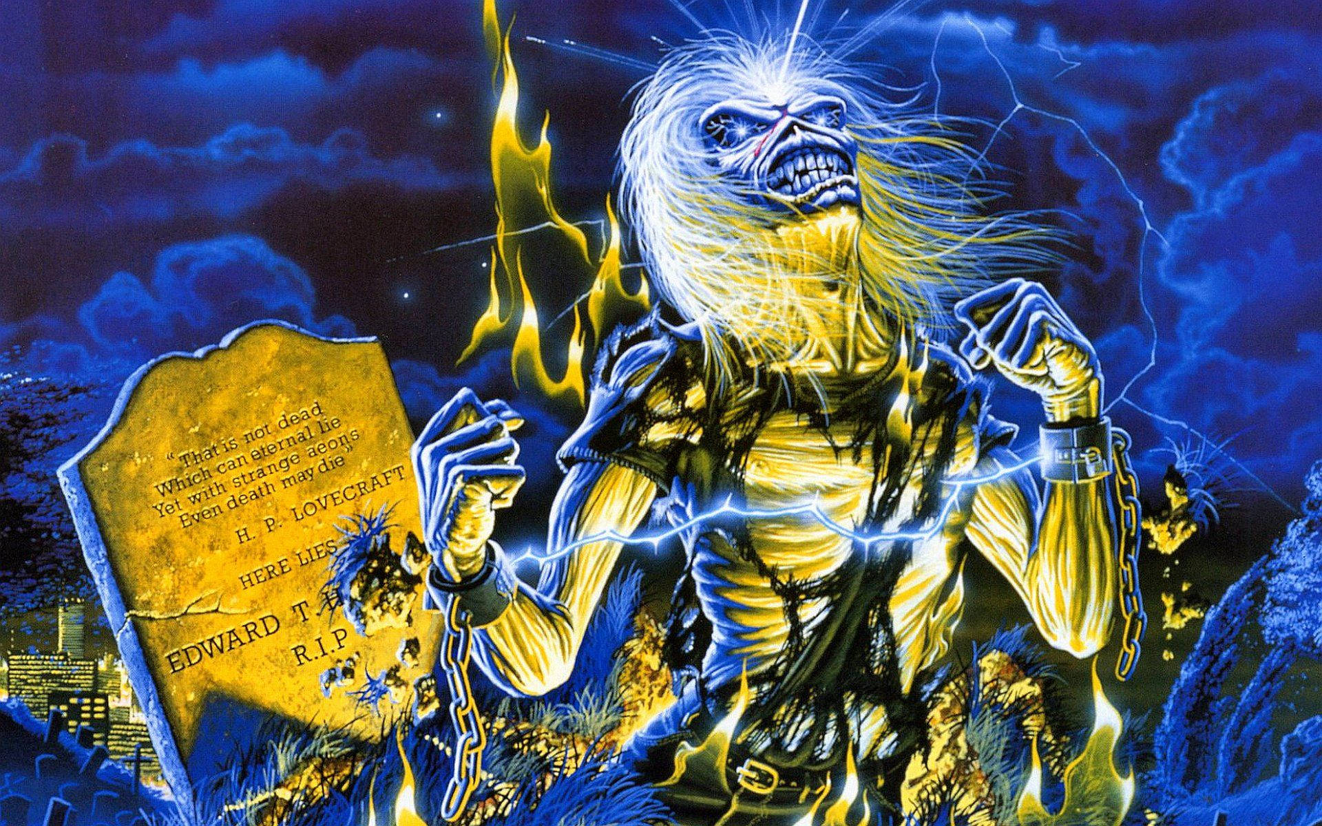 Iron Maiden - Rising from the Grave 壁紙 — 一個擁有狂野白髮和鎖鏈的骷髏形象從火焰中爆發，旁邊是刻有 H P Lovecraft 名字的墓碑，背景是暴風雨的夜空。