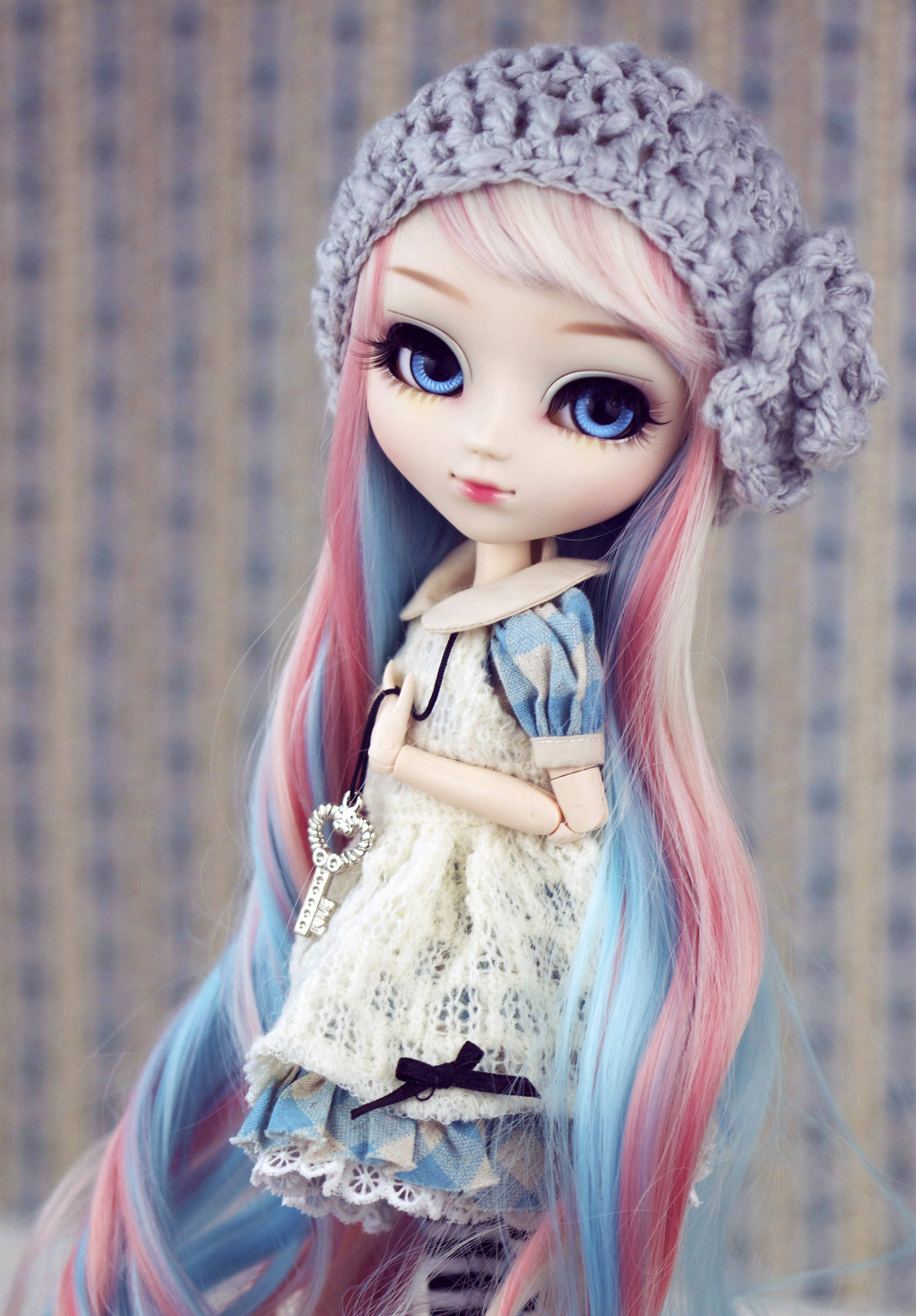 Doll 桌布 壁紙 — 一個擁有粉彩粉紅和藍色頭髮的娃娃，戴著灰色針織帽和蕾絲裙，手持鑰匙吊墜。