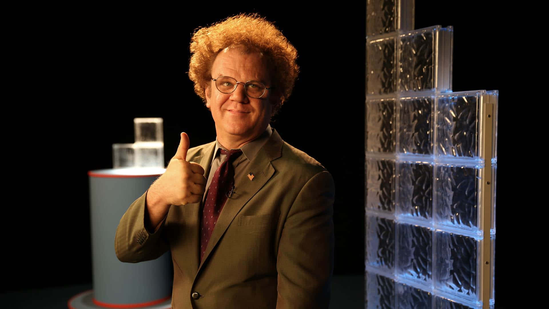 John C. Reilly 桌布 壁紙 — 一個擁有紅色捲髮和眼鏡的男人在一個帶有發光玻璃磚結構的工作室裏豎起大拇指。