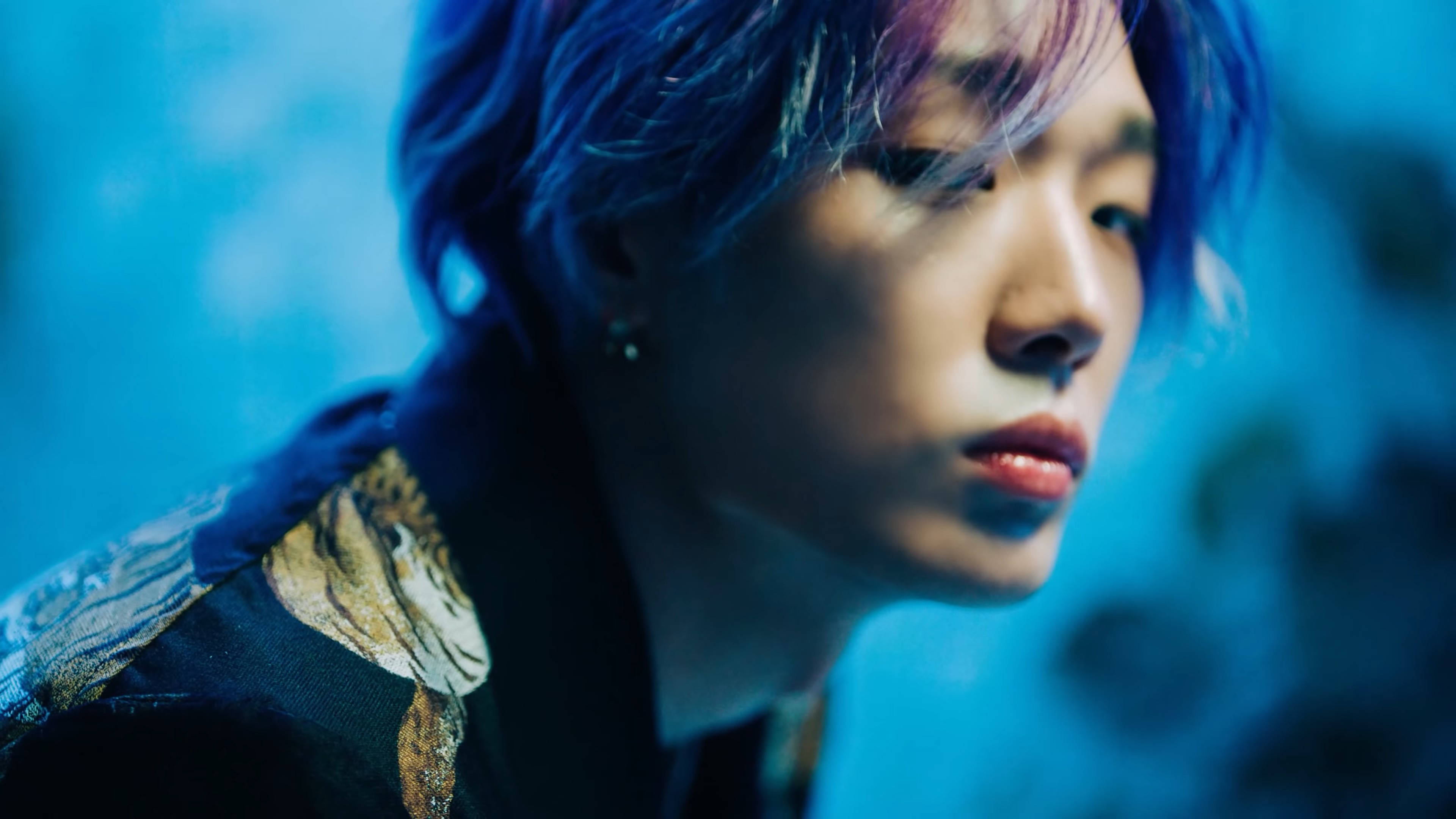 Kpop iKON Bobby 壁紙 — 一個擁有藍色和紫色頭髮的人，在清涼的藍色模糊背景下若有所思地凝視著。
