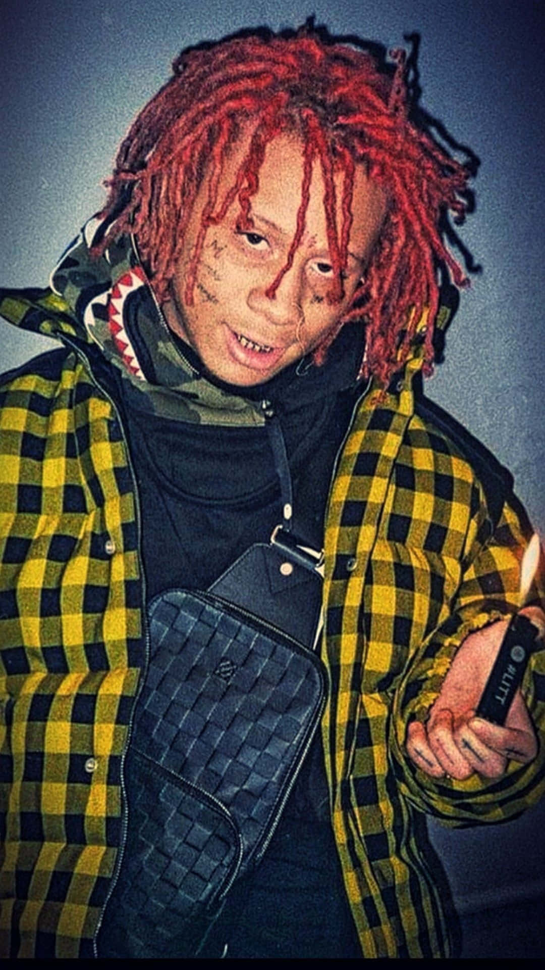 trippie redd 桌布 壁紙 — 一個擁有鮮紅色辮子頭和面部紋身的人，穿著黃黑格紋外套，手持點燃的打火機。