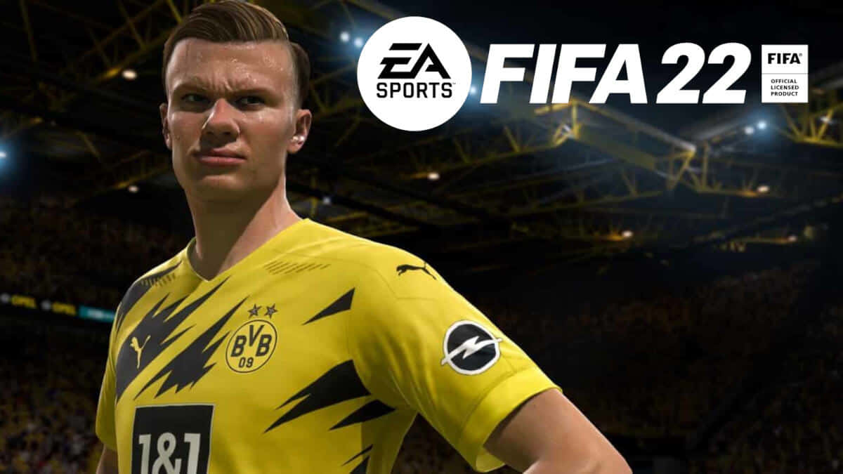 Fifa 22 桌布 壁紙 — 一個數碼渲染的足球運動員身穿黃色多蒙特球衣，在明亮的燈光下自信地站在擠滿觀眾的球場上。