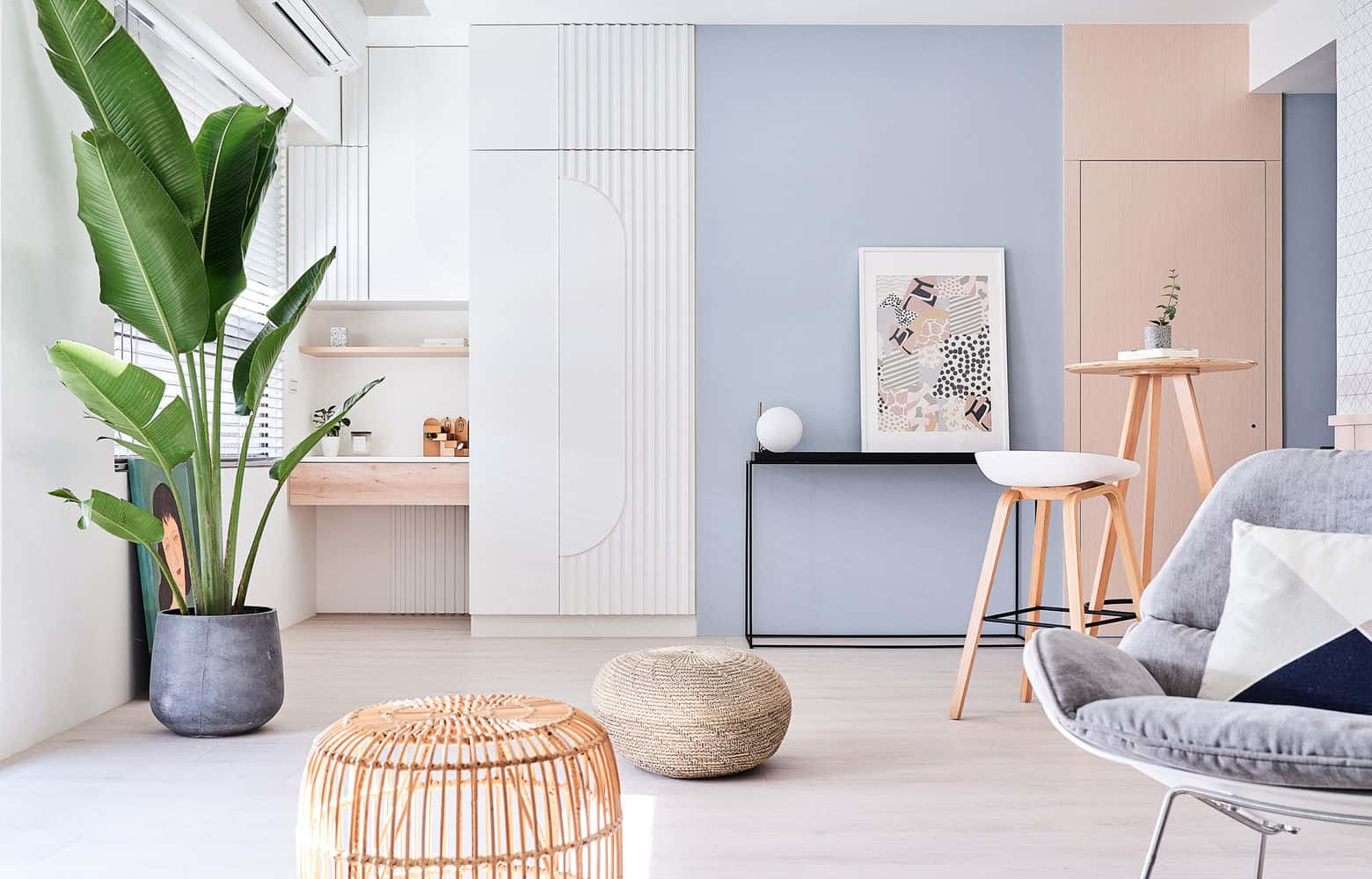 Interior Design 桌布 壁紙 — 一個明亮現代嘅生活空間，有一棵大綠色植物、灰色椅子、編織腳凳同粉藍色嘅特色牆。