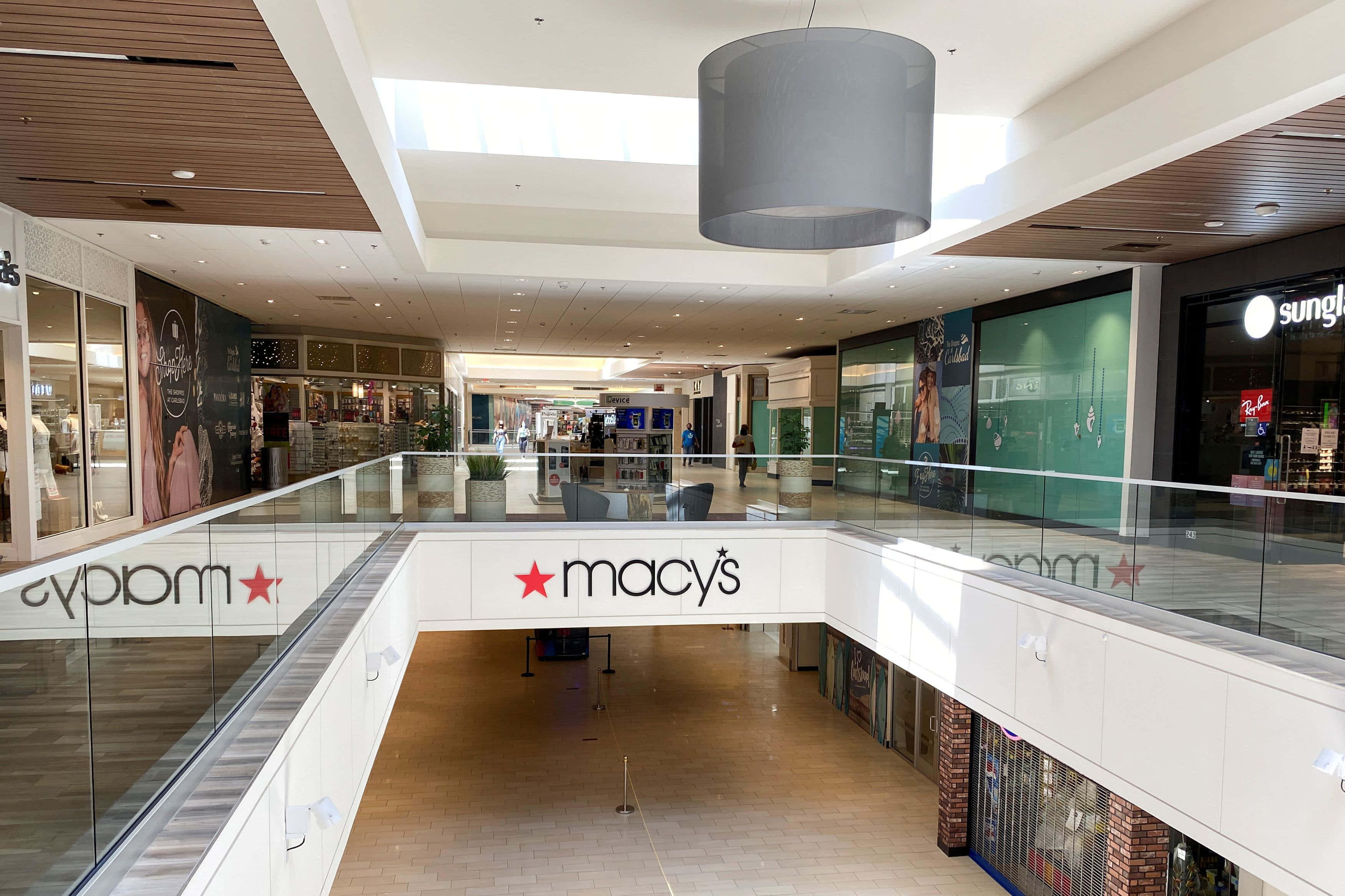 Mall 桌布 壁紙 — 一個明亮現代購物中心內部，玻璃欄杆和木質天花板裝飾下，上下層均可見Macy's和Cyprium商店。