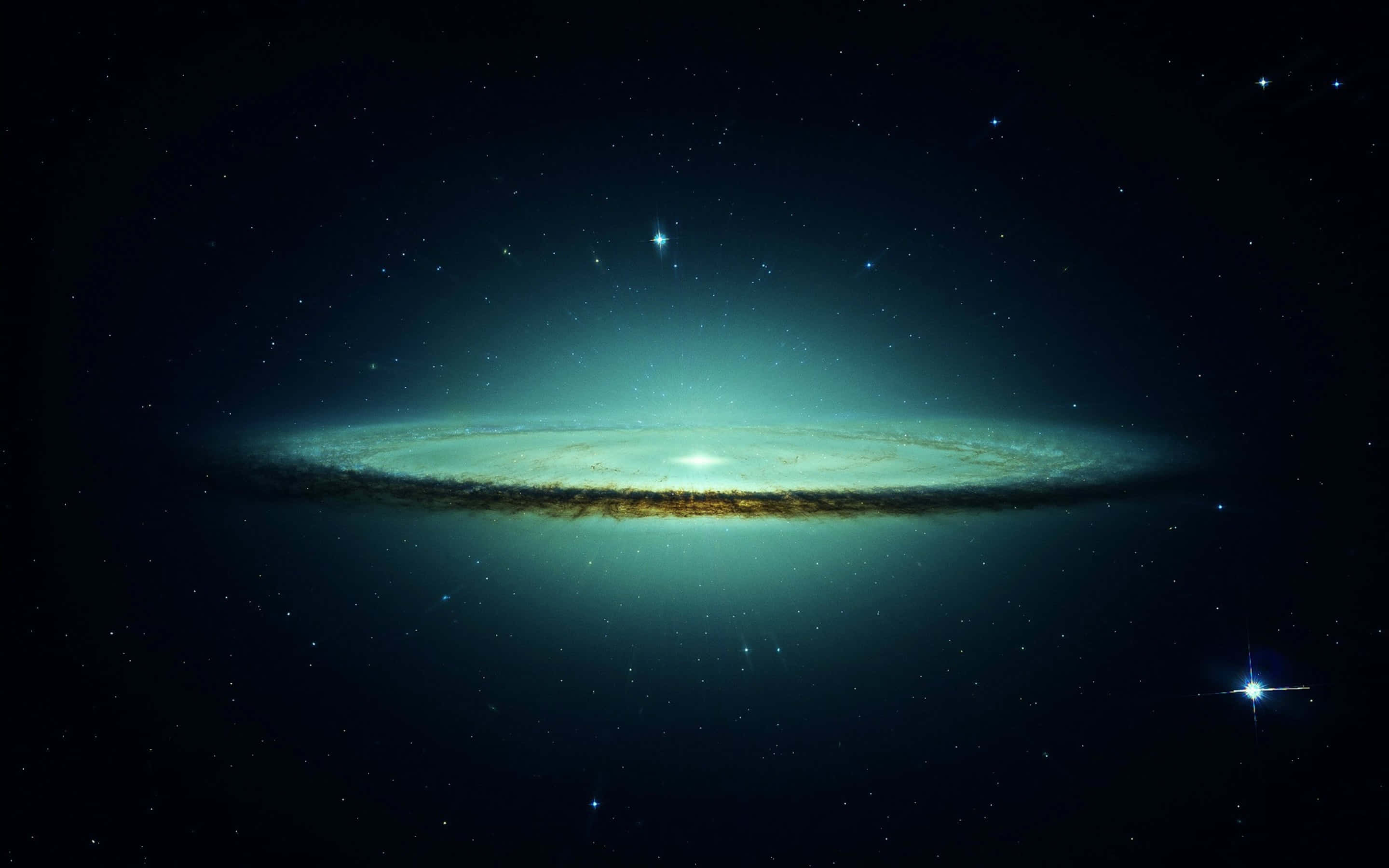 Trippy Space 桌布 壁紙 — 一個明亮的螺旋星系在宇宙黑暗中，以藍綠色和金色色調在星場背景下發光。
