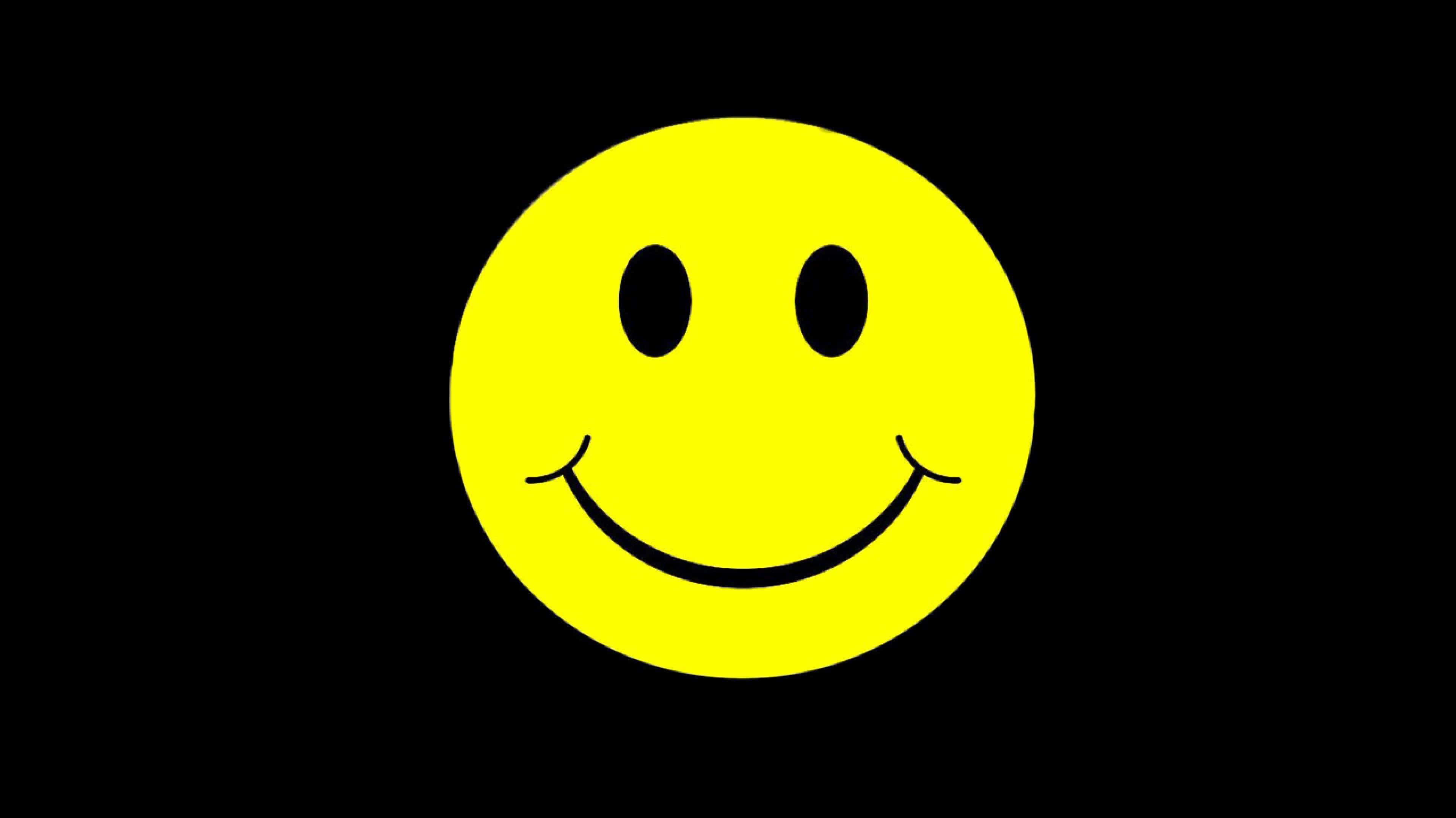 Smiley 桌布 壁紙 — 一個明亮的黃色笑臉，帶有黑色眼睛和彎曲的嘴巴，居中在純黑色背景上。