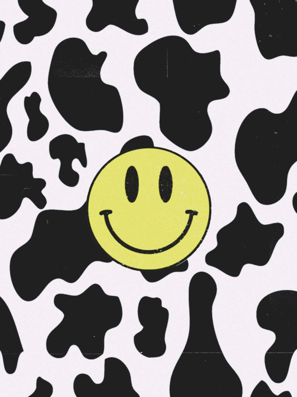 Aesthetic Smiley Face 桌布 壁紙 — 一個明亮的黃色笑臉位於黑白乳牛紋背景中央，帶有細微紋理。