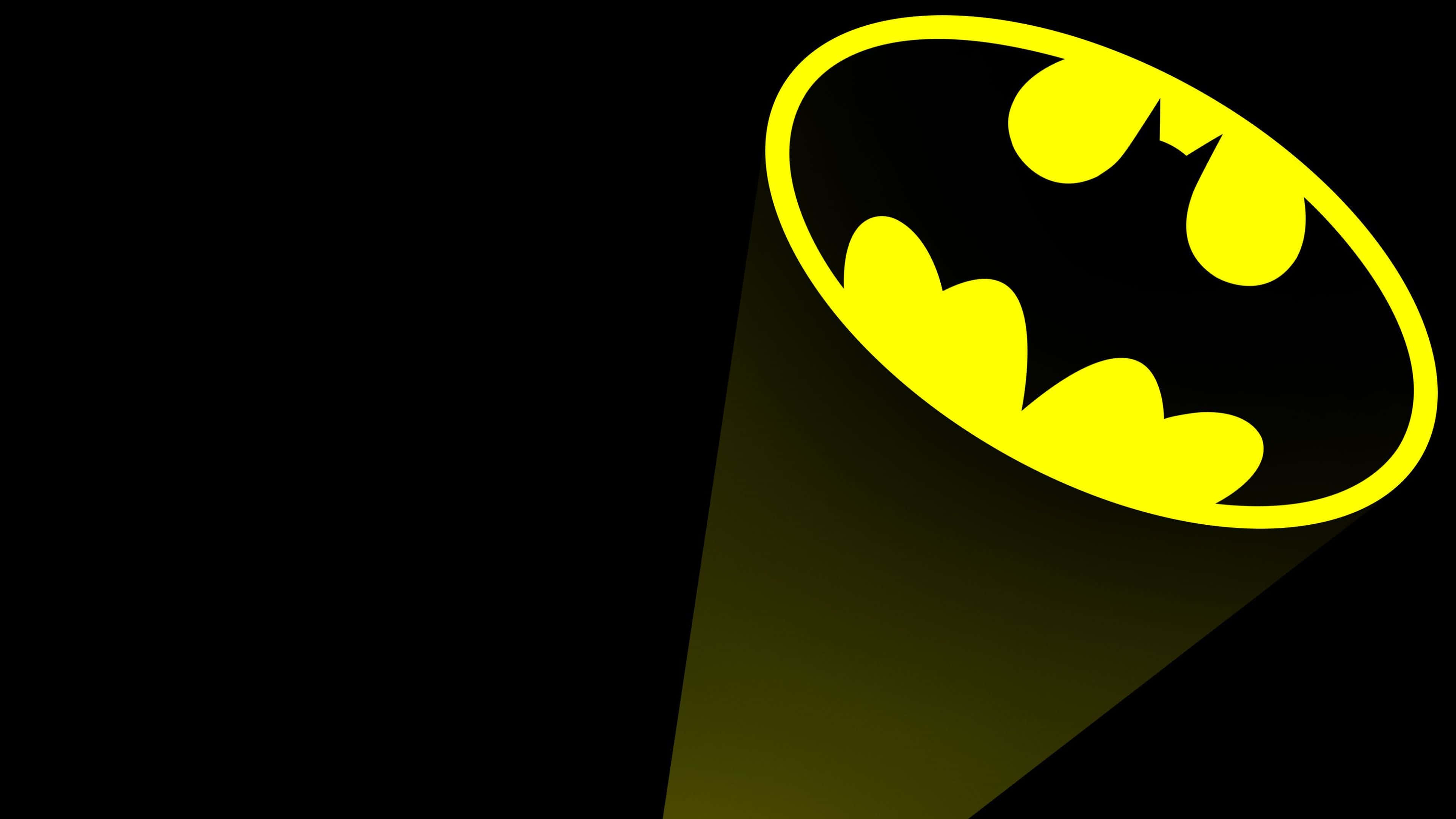 Bat Signal 桌布 壁紙 — 一個明亮的黃色蝙蝠俠標誌，在黑色背景上被聚光燈照亮。