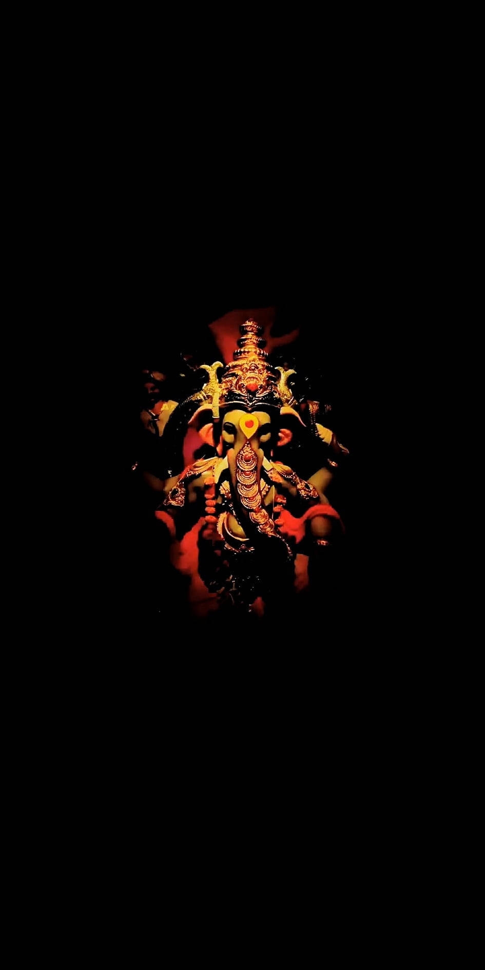 hindu iPhone 桌布 壁紙 — 一個昏暗燈光下、裝飾華麗的多臂金色神像，戴著皇冠，在黑色背景中發光。