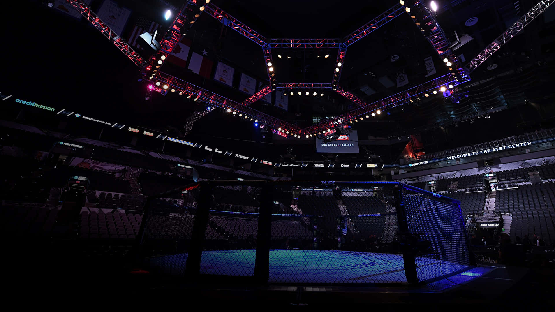 UFC 桌布 壁紙 — 一個昏暗的MMA八角籠，在空蕩蕩的場館中，舞台燈光璀璨，可見「Welcome to the AT&T Center」。