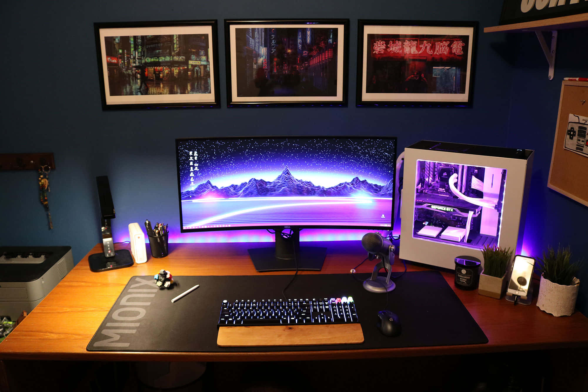 Gaming Pc Setup 桌布 壁紙 — 一個時尚的遊戲設置，在曲面顯示器上帶有發光的紫色山脈壁紙，以及木桌上發光的PC機箱。