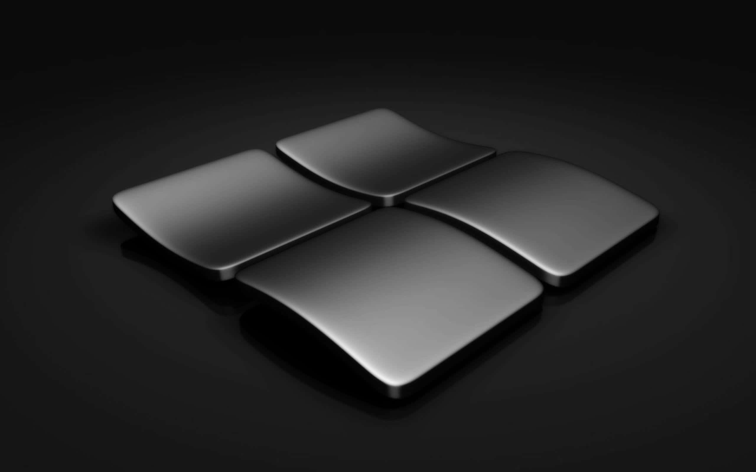 Black Windows 桌布 壁紙 — 一個時尚的金屬Windows標誌在深黑色背景上柔和地發光，柔和的燈光突出其彎曲表面。