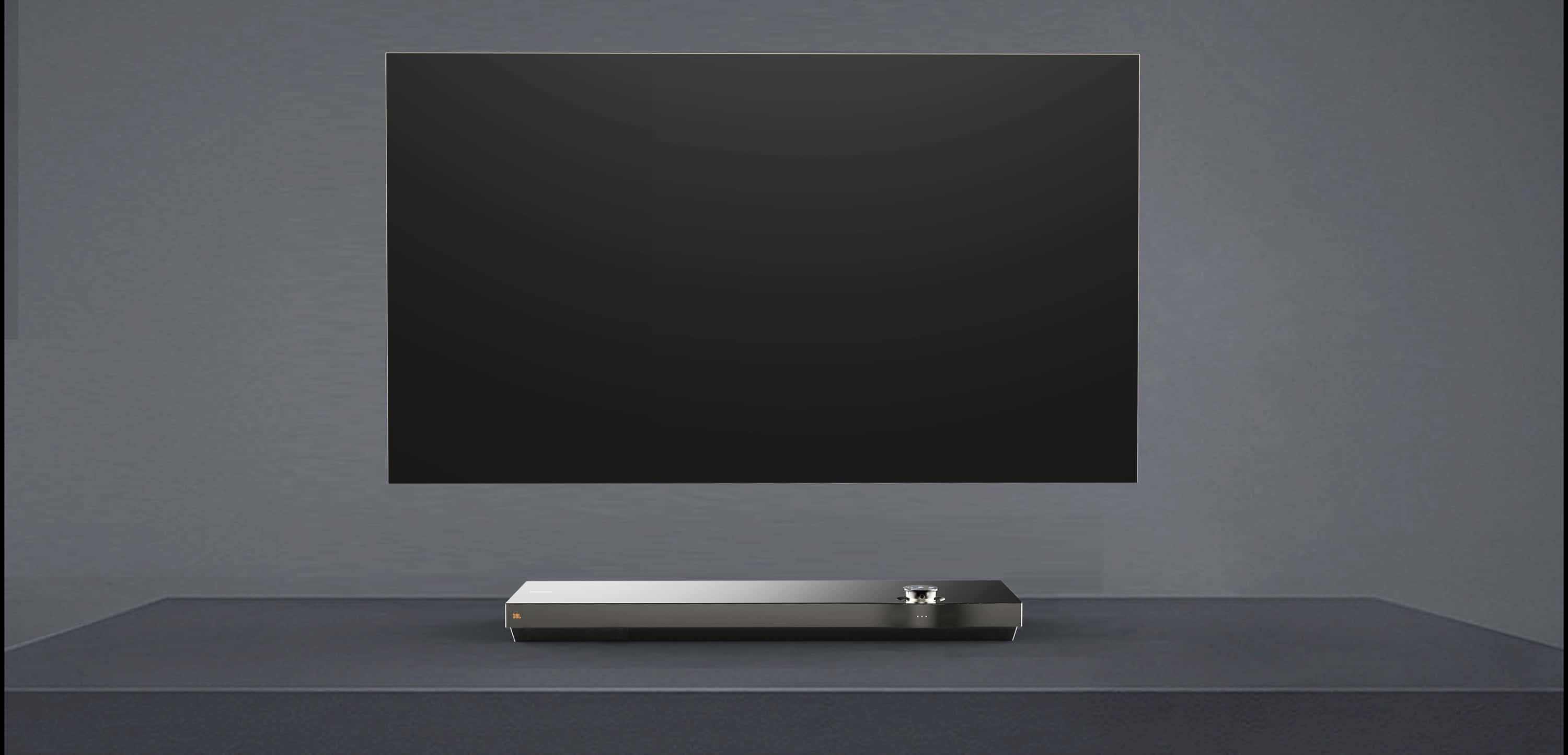 tv 桌布 壁紙 — 一個時尚的銀色soundbar置中放在一個深色支架上，下方是一部大型黑色電視，背景是簡約灰色牆壁。