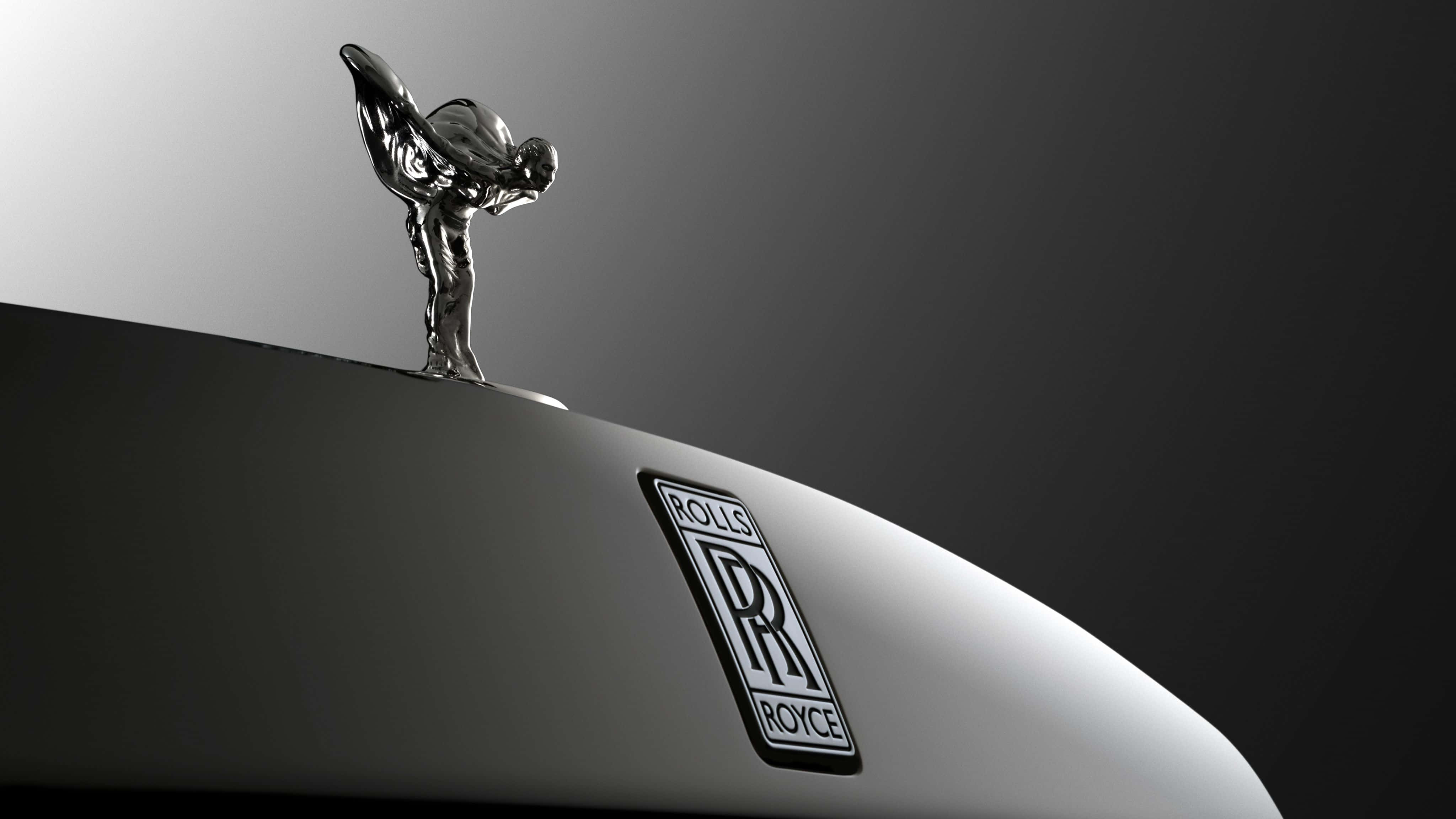 Rolls Royce 桌布 壁紙 — 一個時尚的銀色勞斯萊斯引擎蓋裝飾和徽章在戲劇性的工作室燈光下，在漸變灰色背景上閃閃發光。