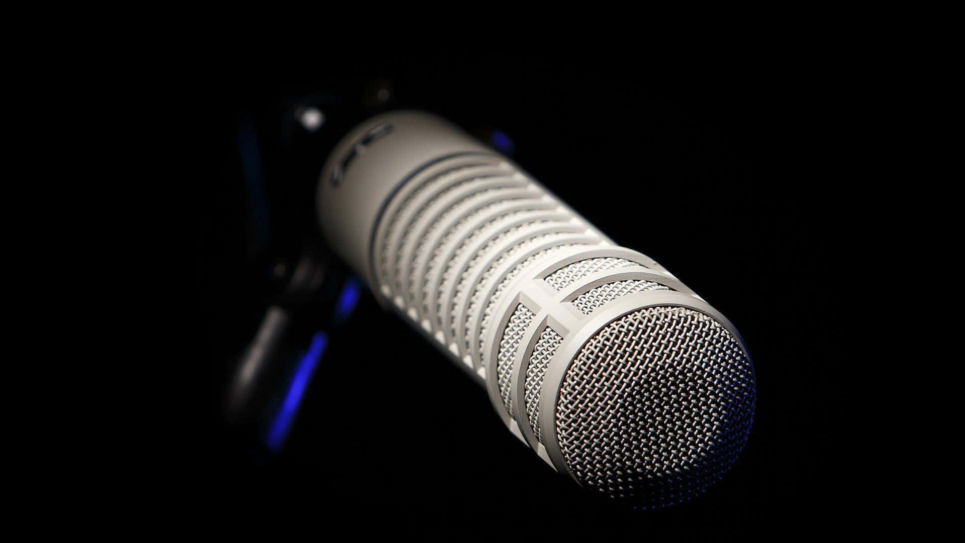 Voice 桌布 壁紙 — 一個時尚的銀色電容咪高峰，帶有網格罩，在深黑色背景下柔和發光。