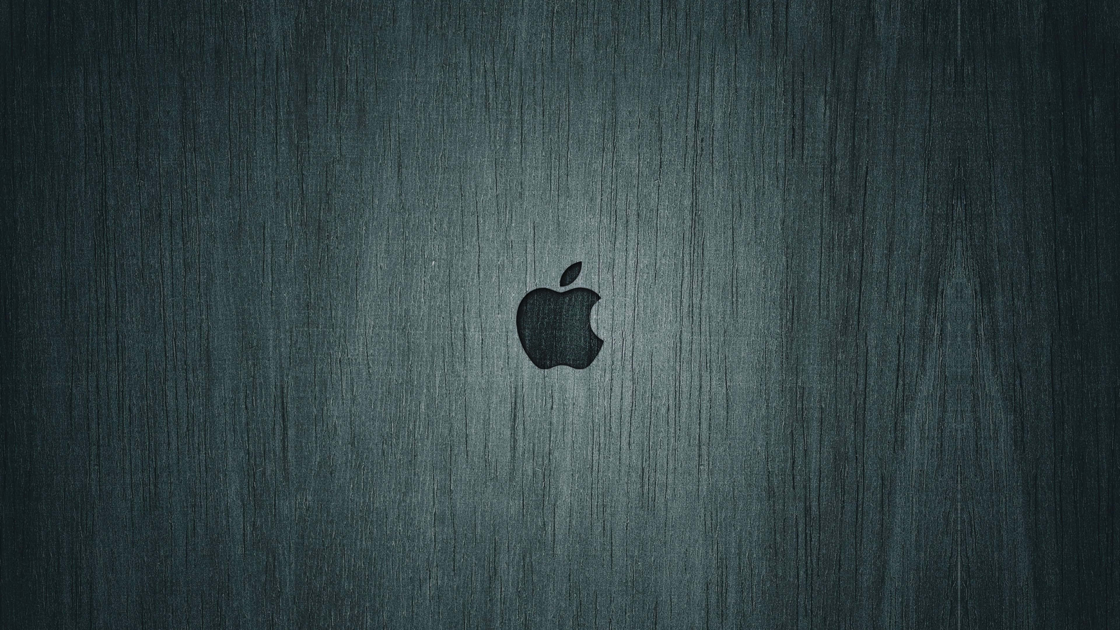 4K Apple 桌布 壁紙 — 一個時尚的黑色Apple標誌，居中放置在帶有細微垂直紋理的拉絲深青綠色金屬表面上。