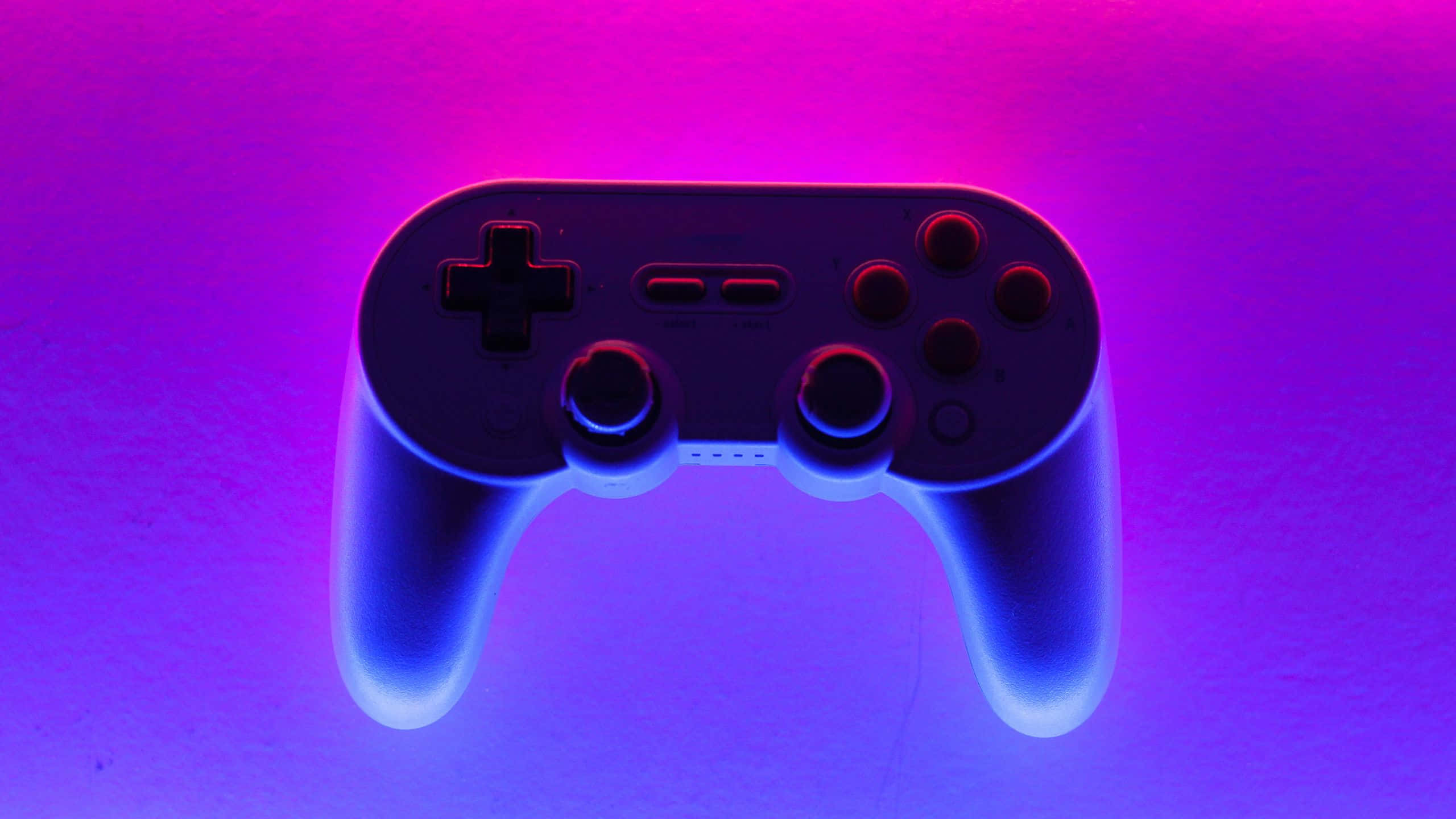 Gaming Banner 桌布 壁紙 — 一個時尚的黑色遊戲控制器在漸變背景上發出鮮豔的藍色和紫色霓虹光。