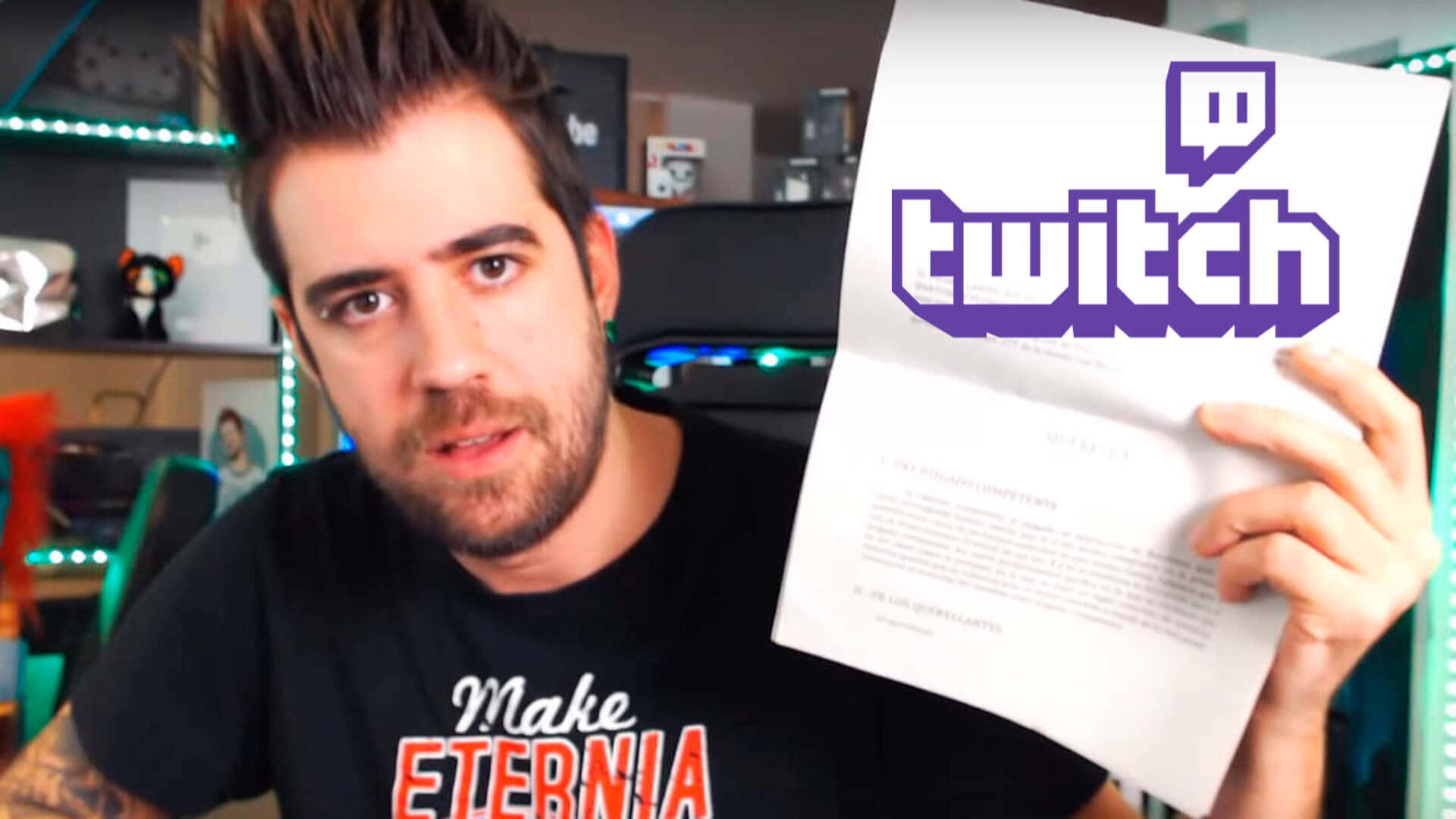 Minecraft Twitch Streamers 桌布 壁紙 — 一個有尖刺頭髮和鬍鬚的男人在一個有霓虹燈裝飾的明亮遊戲室裡拿著一個Twitch字母。