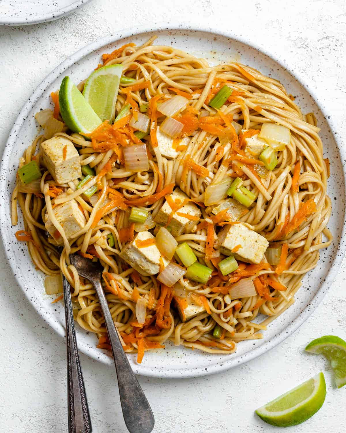 Noodles 桌布 壁紙 — 一個有斑點的白色碟子盛載著色彩鮮豔的炒麵，配以豆腐、紅蘿蔔、蔥和青檸角。
