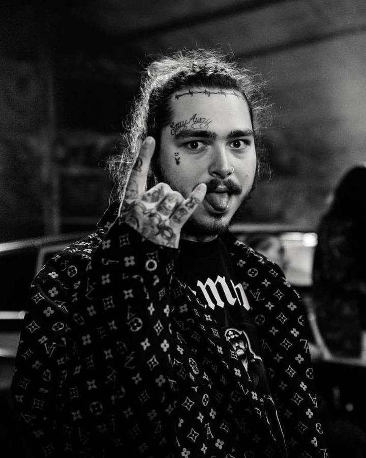 Post Malone 桌布 壁紙 — 一個有紋身、留鬍鬚的男人做出手勢並伸出舌頭的黑白肖像。