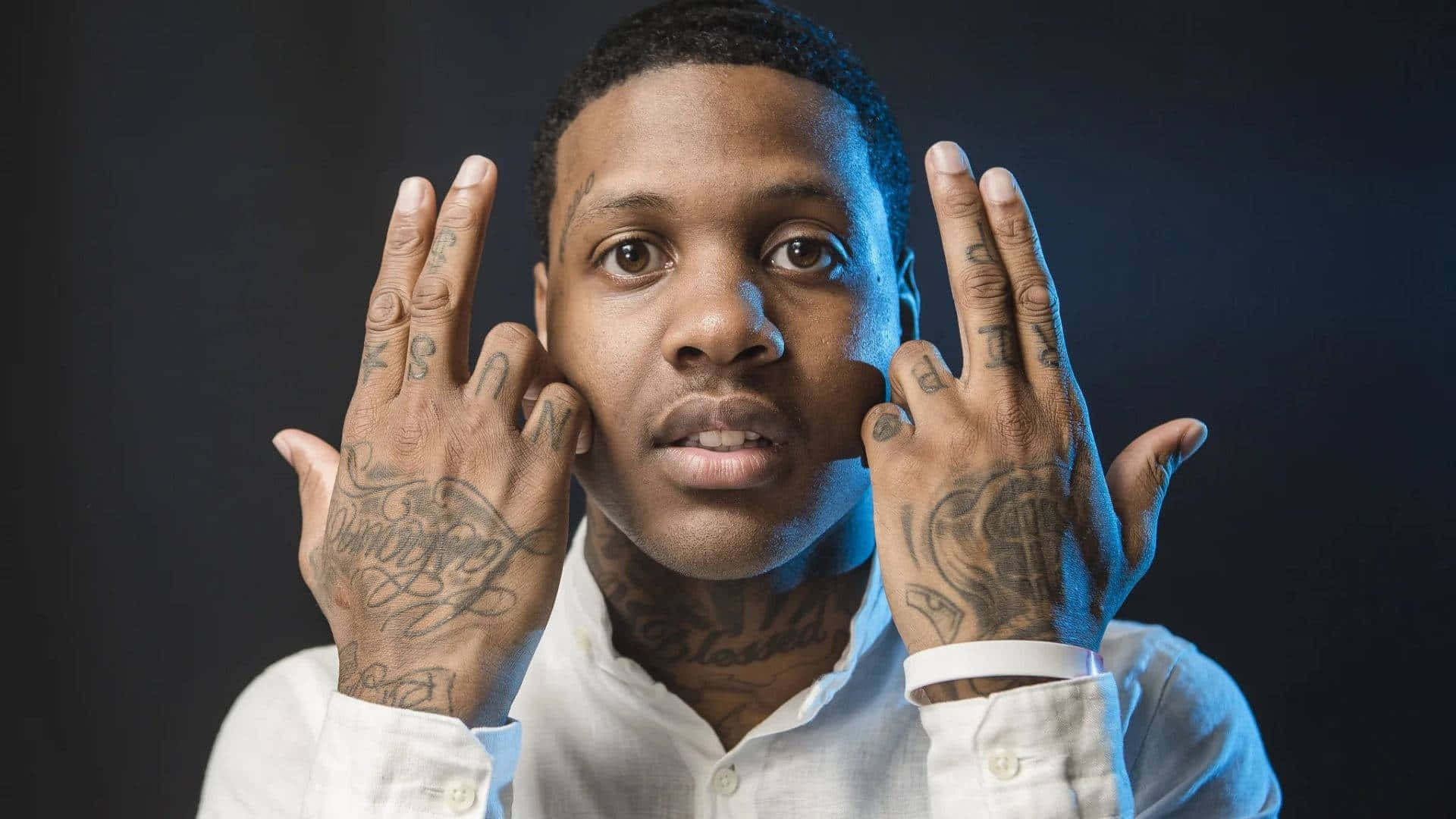 lil durk 桌布 壁紙 — 一個有紋身嘅男人喺黑暗背景前，喺冷藍色燈光下用手框住自己嘅面。