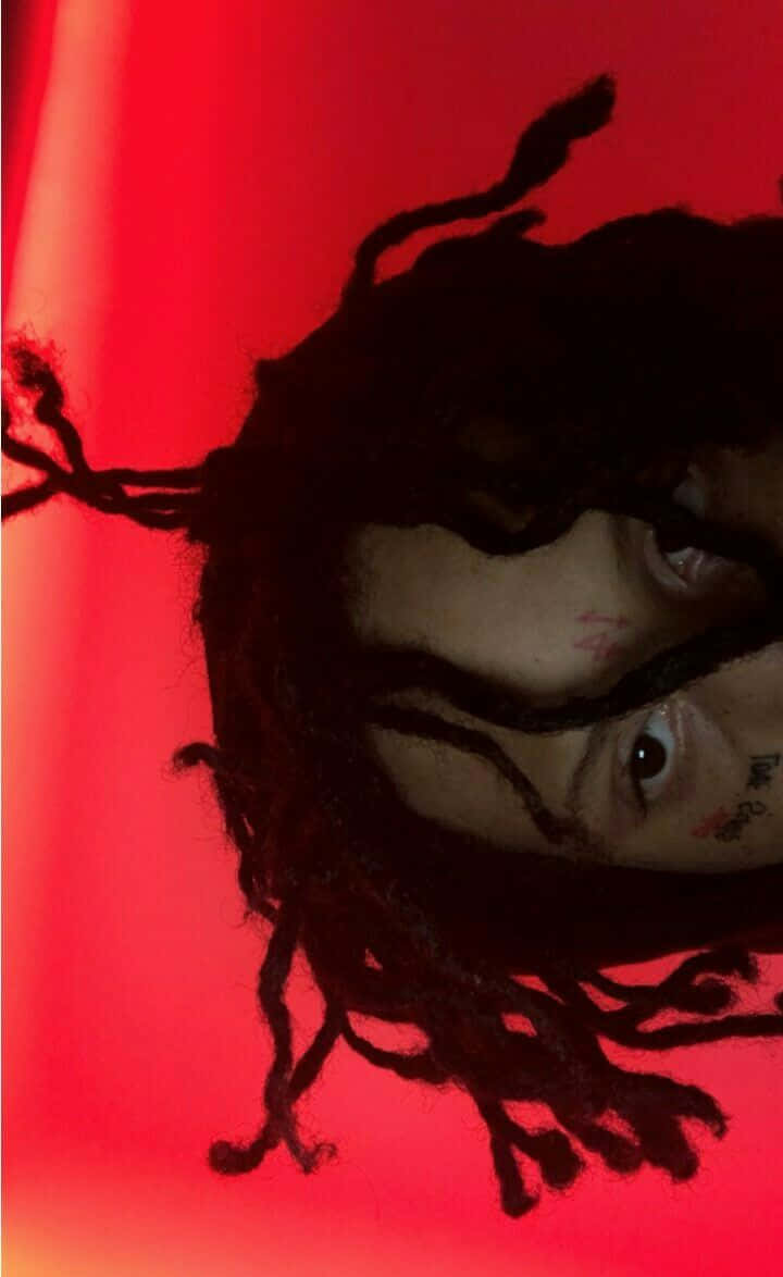 trippie redd 桌布 壁紙 — 一個有辮子頭和紋身的人的特寫，背景是鮮豔的紅色。