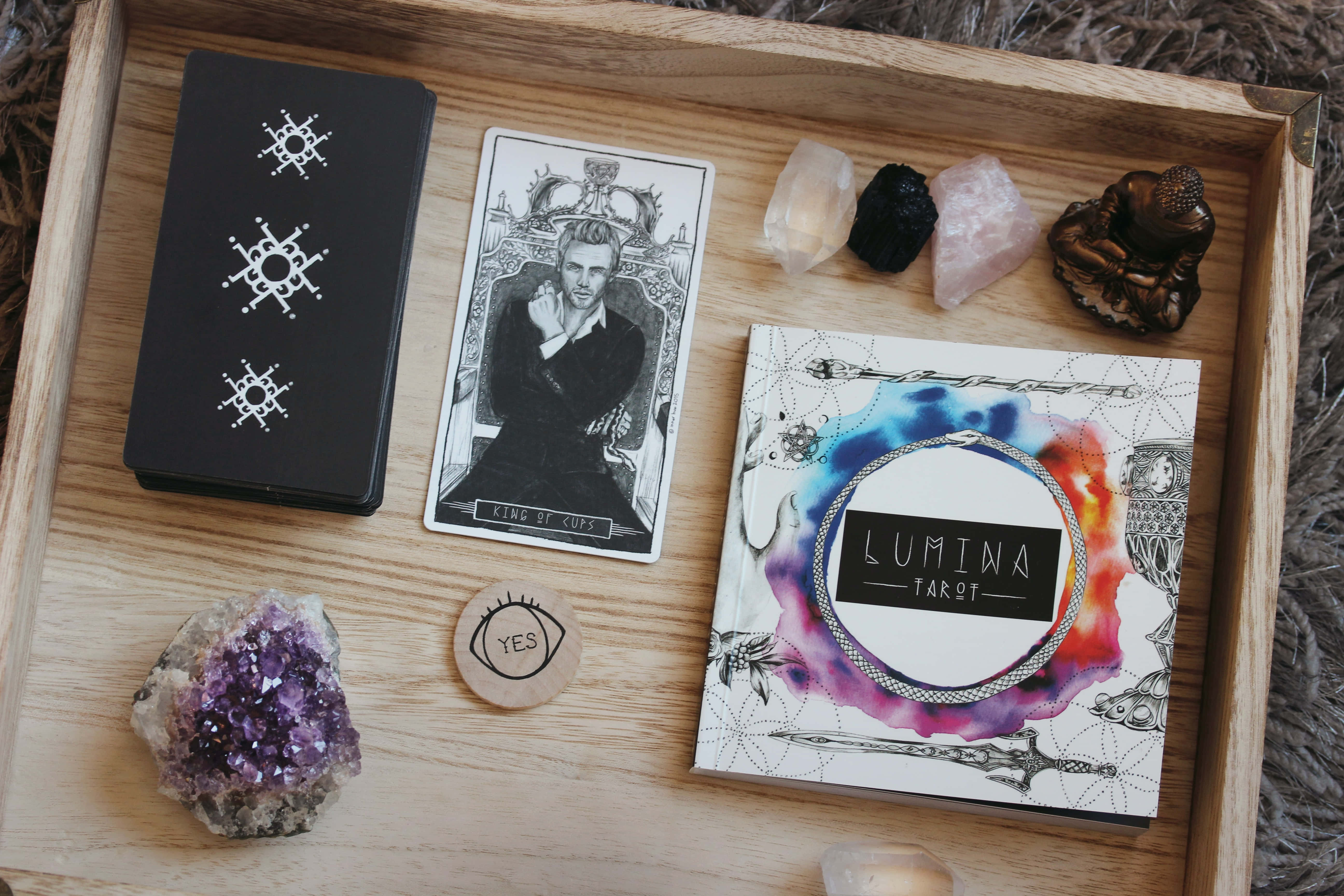 Tarot Card 桌布 壁紙 — 一個木托盤上放有塔羅牌、水晶和佛像，排列在質感地毯上進行靈性解讀。